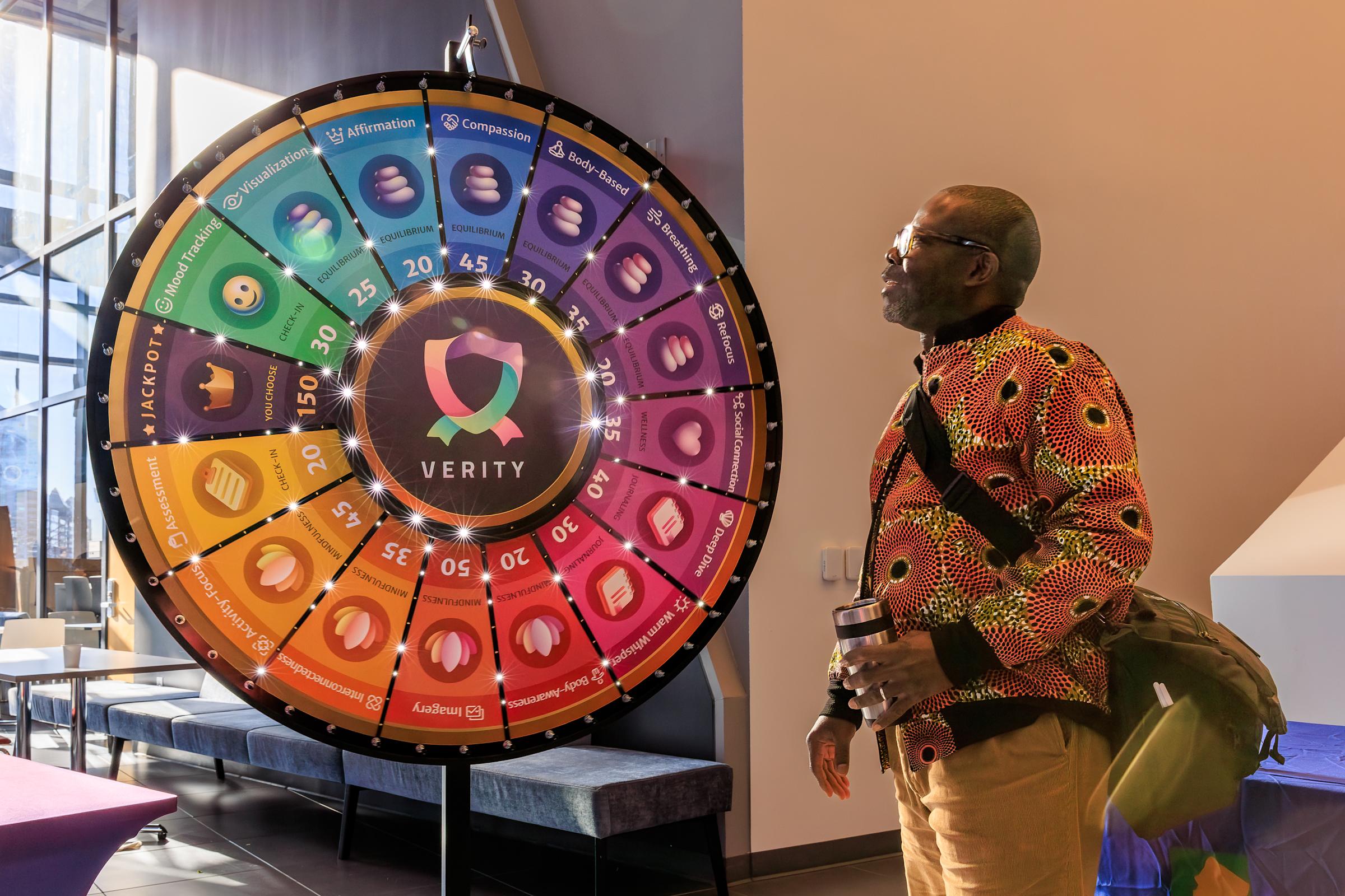 A man stands near a multi-color spinning wheel
