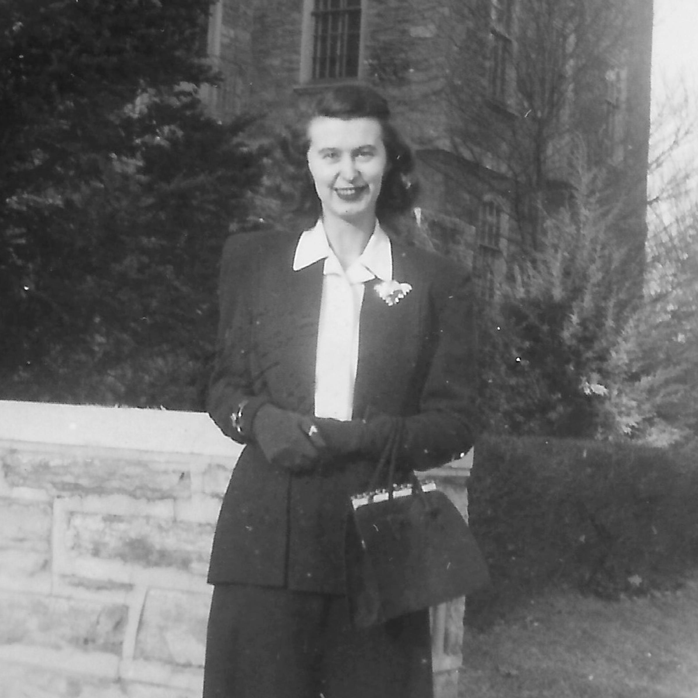 balck and white photo from the 1940s of Fischl in front of a building holding a purse.