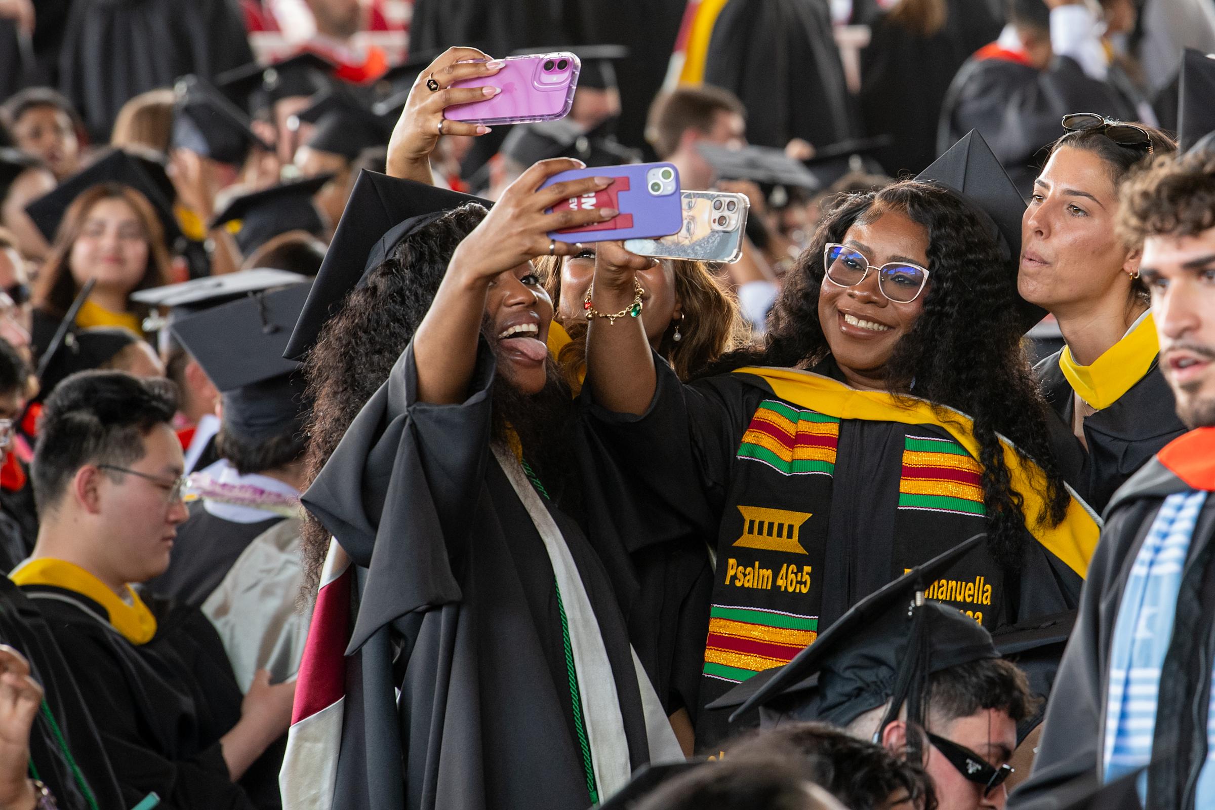 Three women at Commencement hold phones for selfies