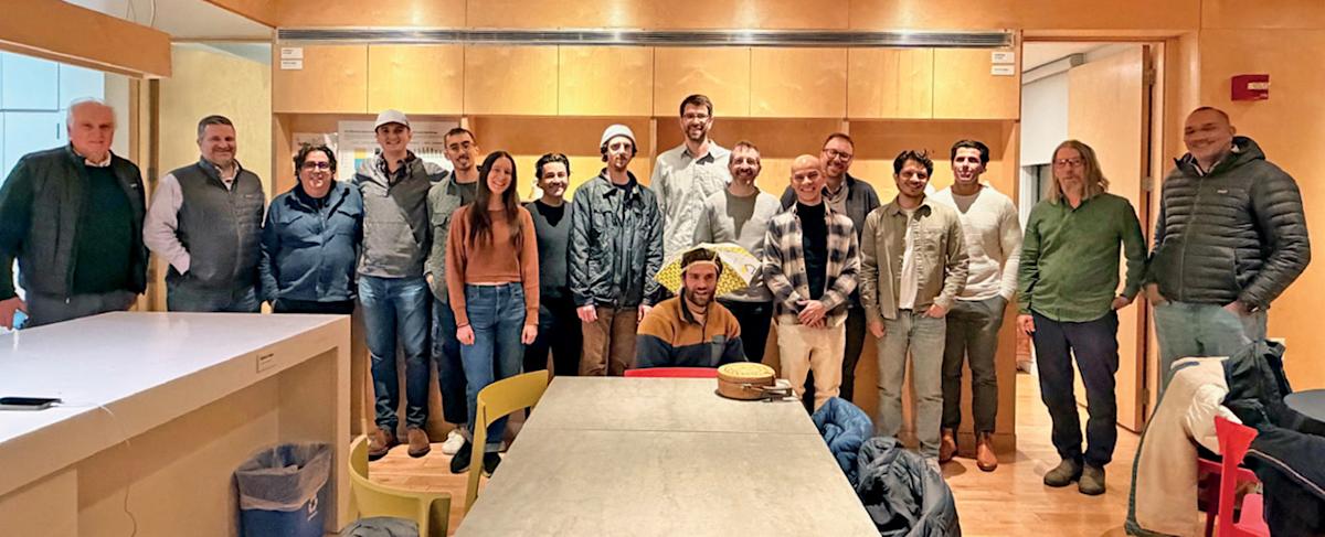 Photo of 17 Stevens alumni and faculty who worked on the SU+RE House project gathered inside the solar house now based at Liberty Science Center.