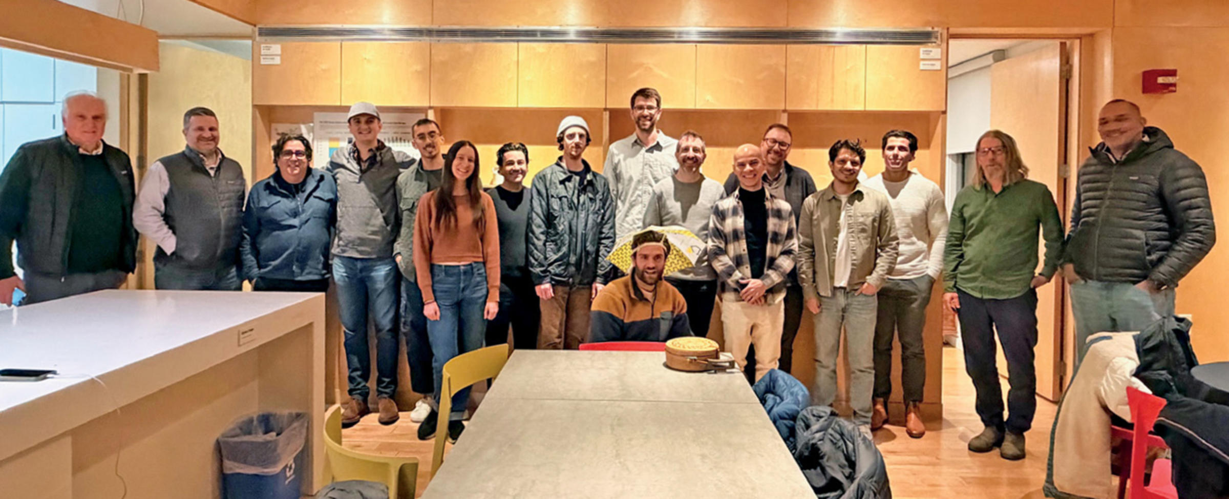 Photo of 17 Stevens alumni and faculty who worked on the SU+RE House project gathered inside the solar house now based at Liberty Science Center.