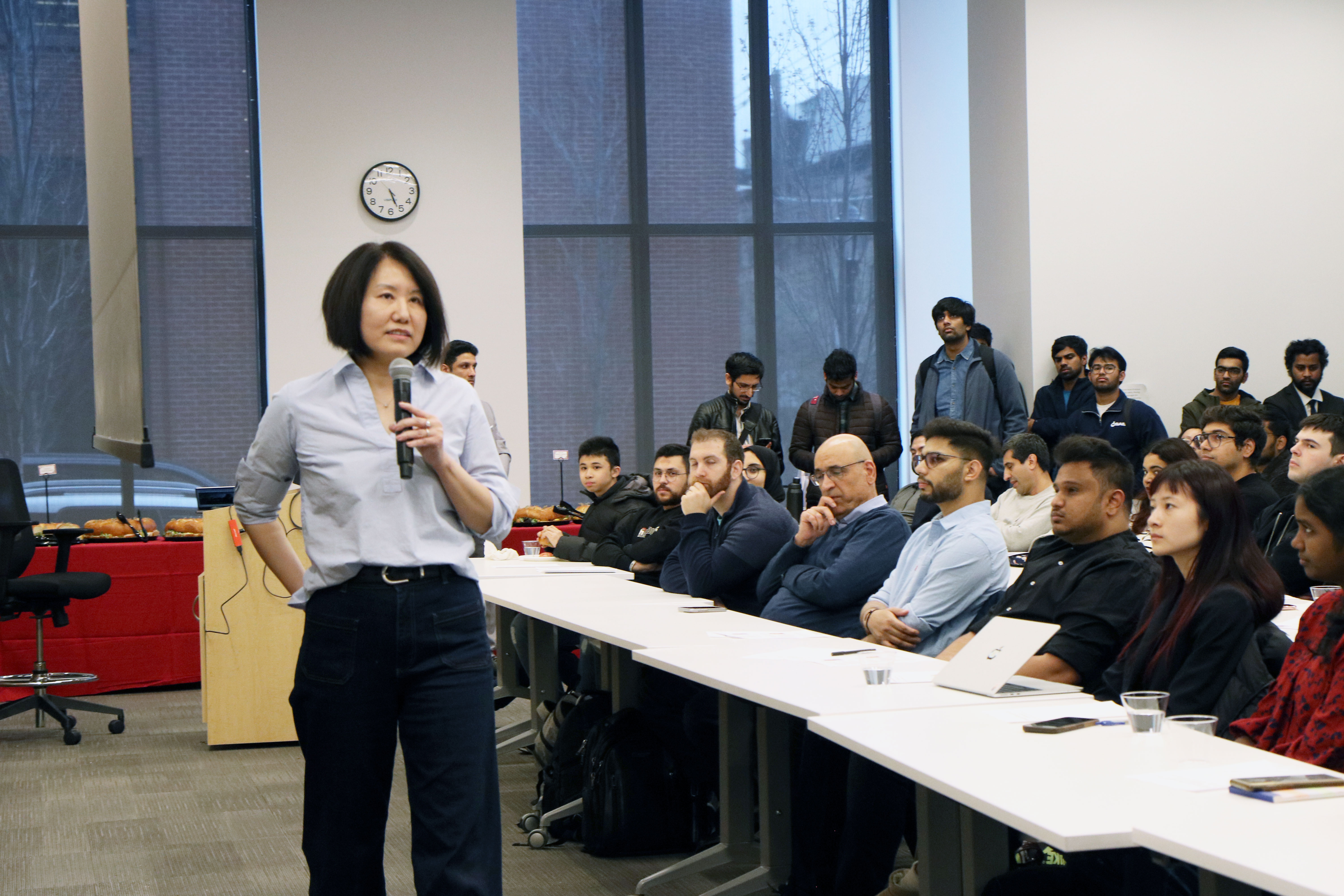 A speaker addresses a full audience of students.