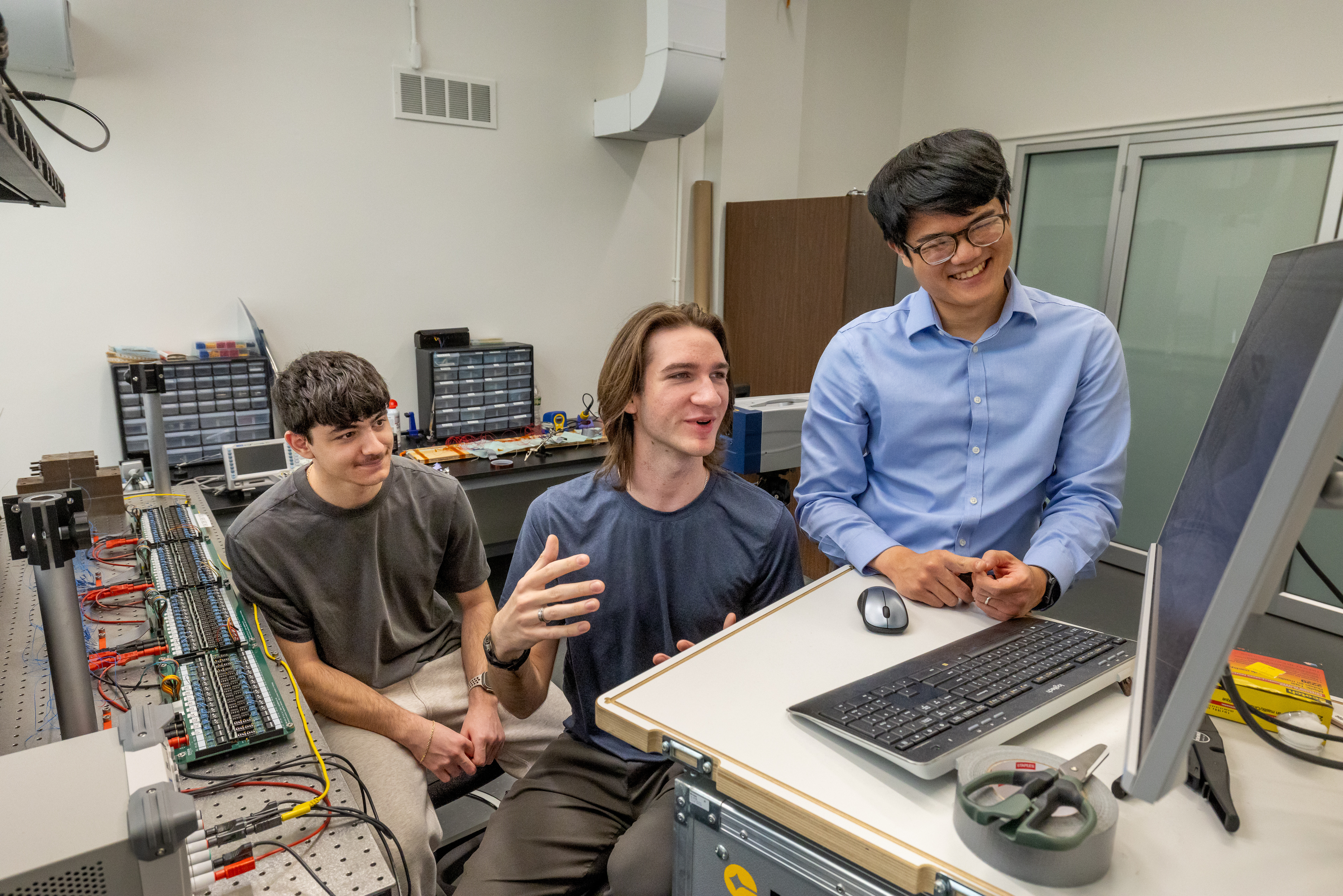 Two students and professor Christopher Sugino looking at a monitor in a mechanical engineering department lab.