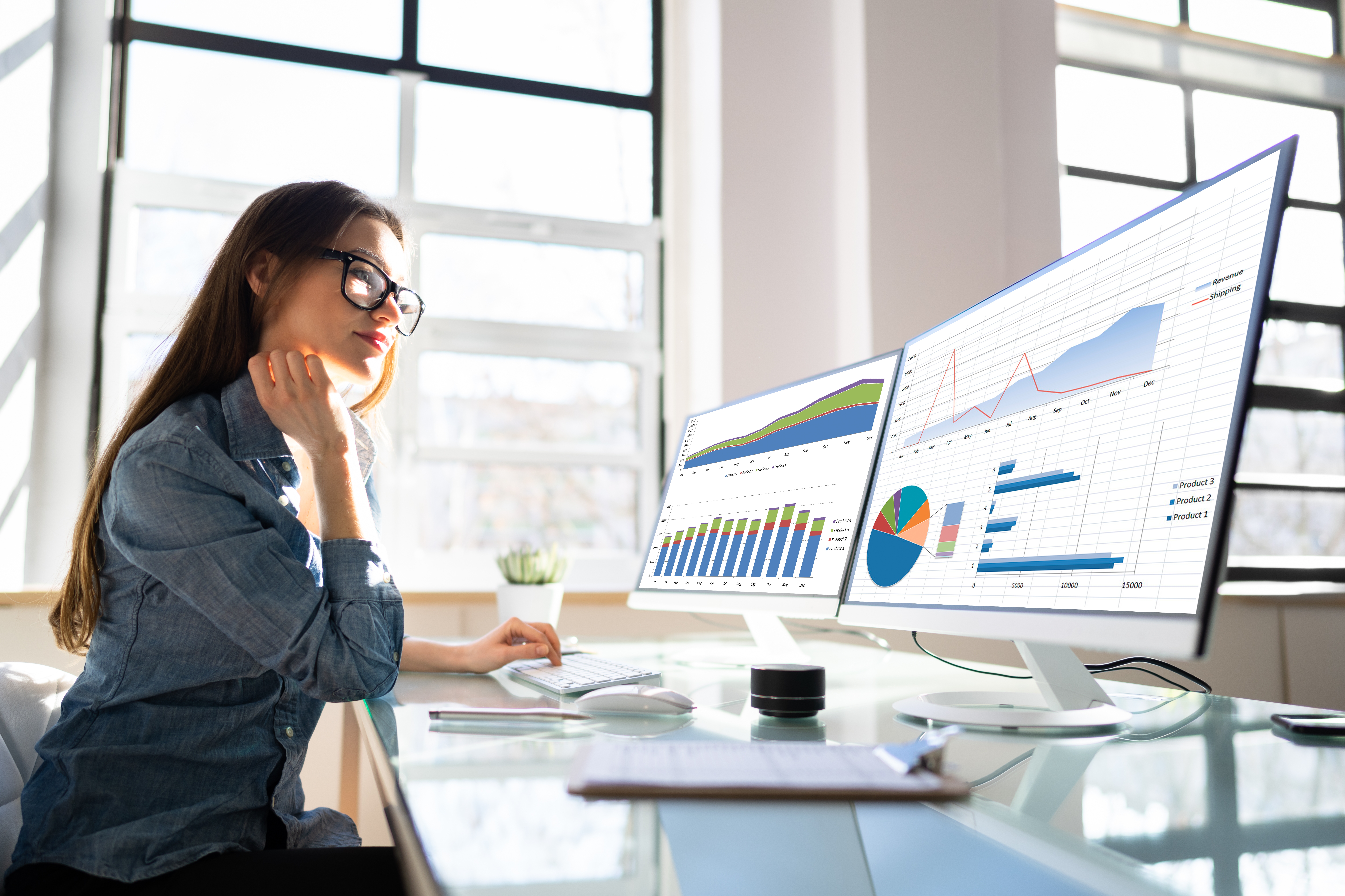 woman looking at charts on two computer screens