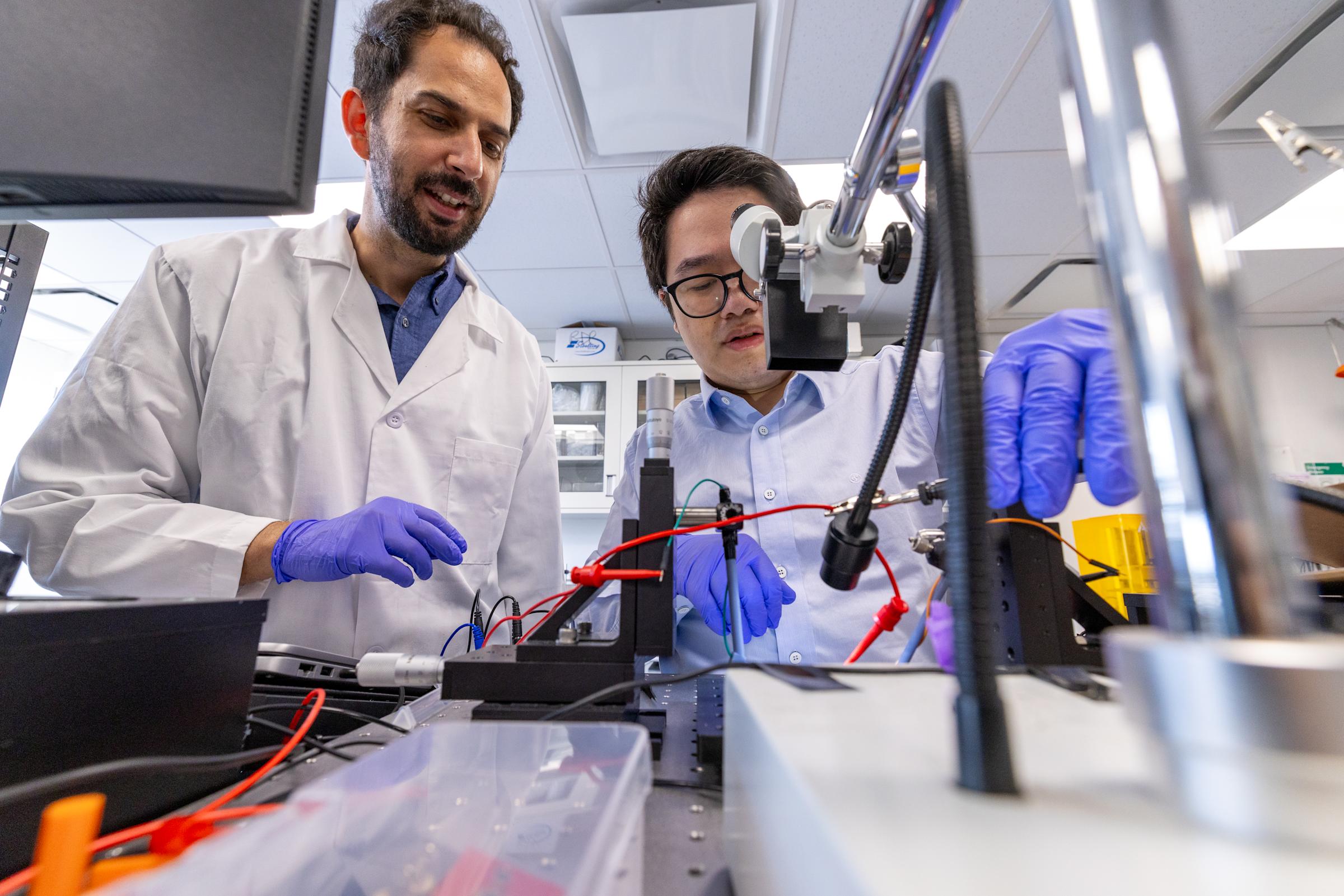 Ilke Uguz and a student at right working in a lab while wearing gloves.