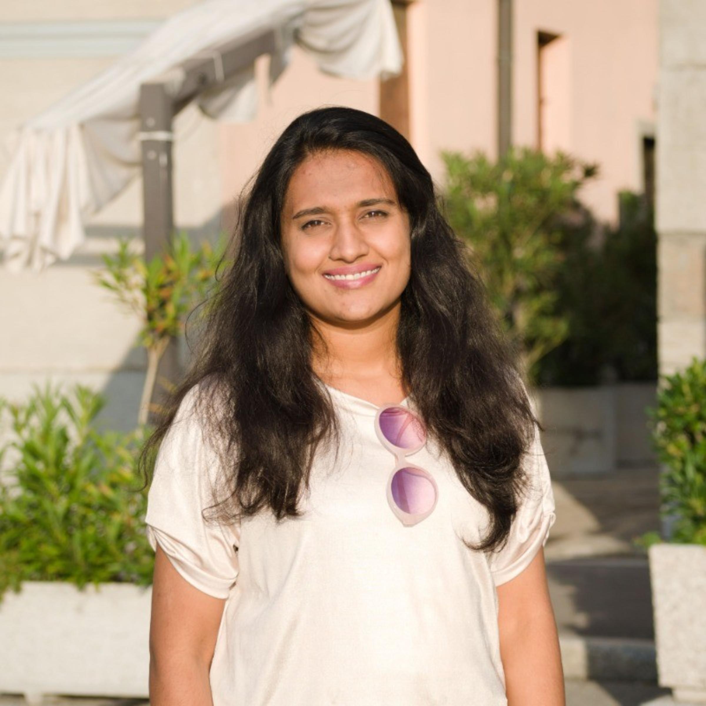 A photo from the waist up of Sugganahalli Natesh Babu standing outdoors with plants in the background.