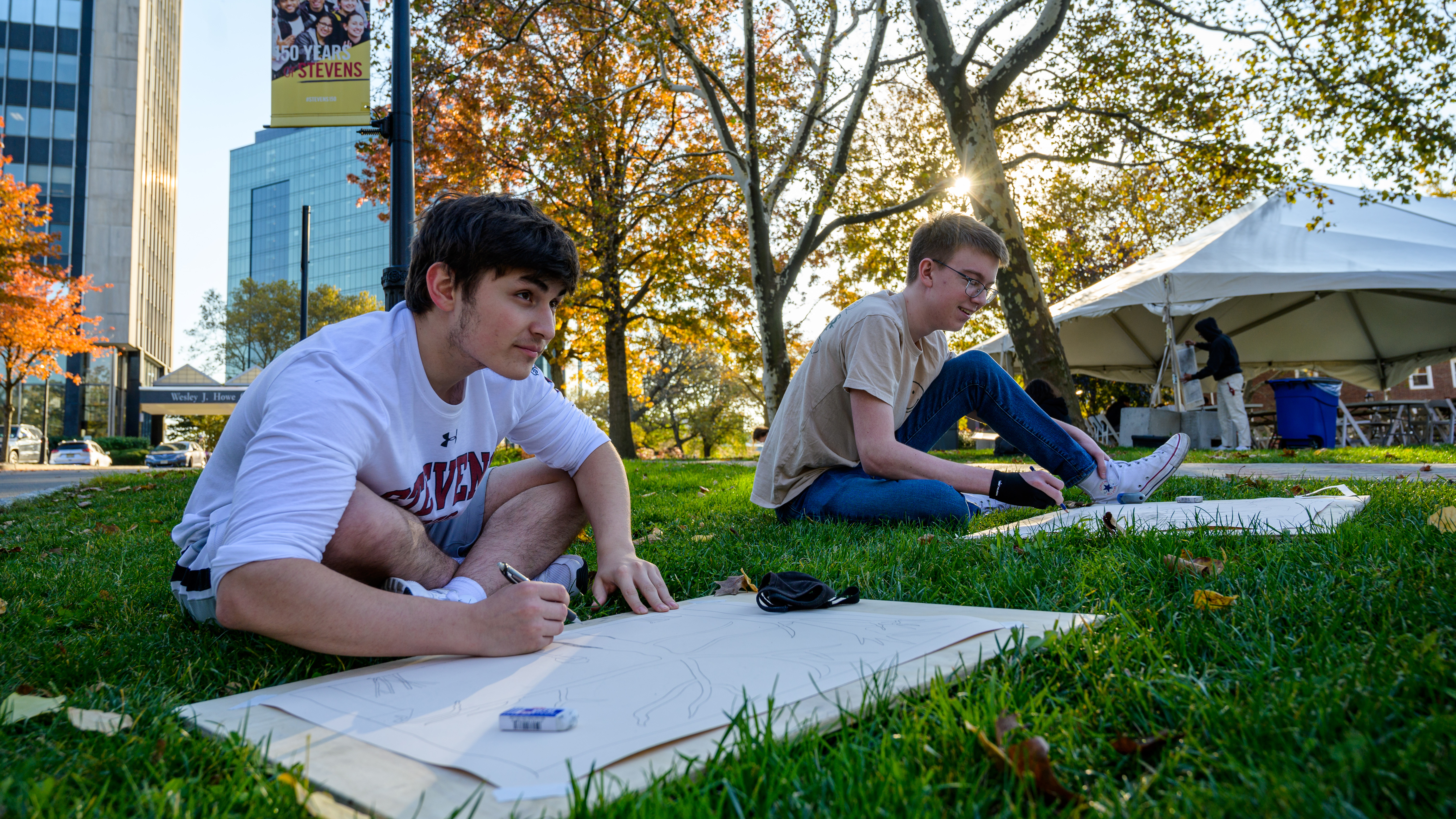 Two students outdors on campus drawing a building.