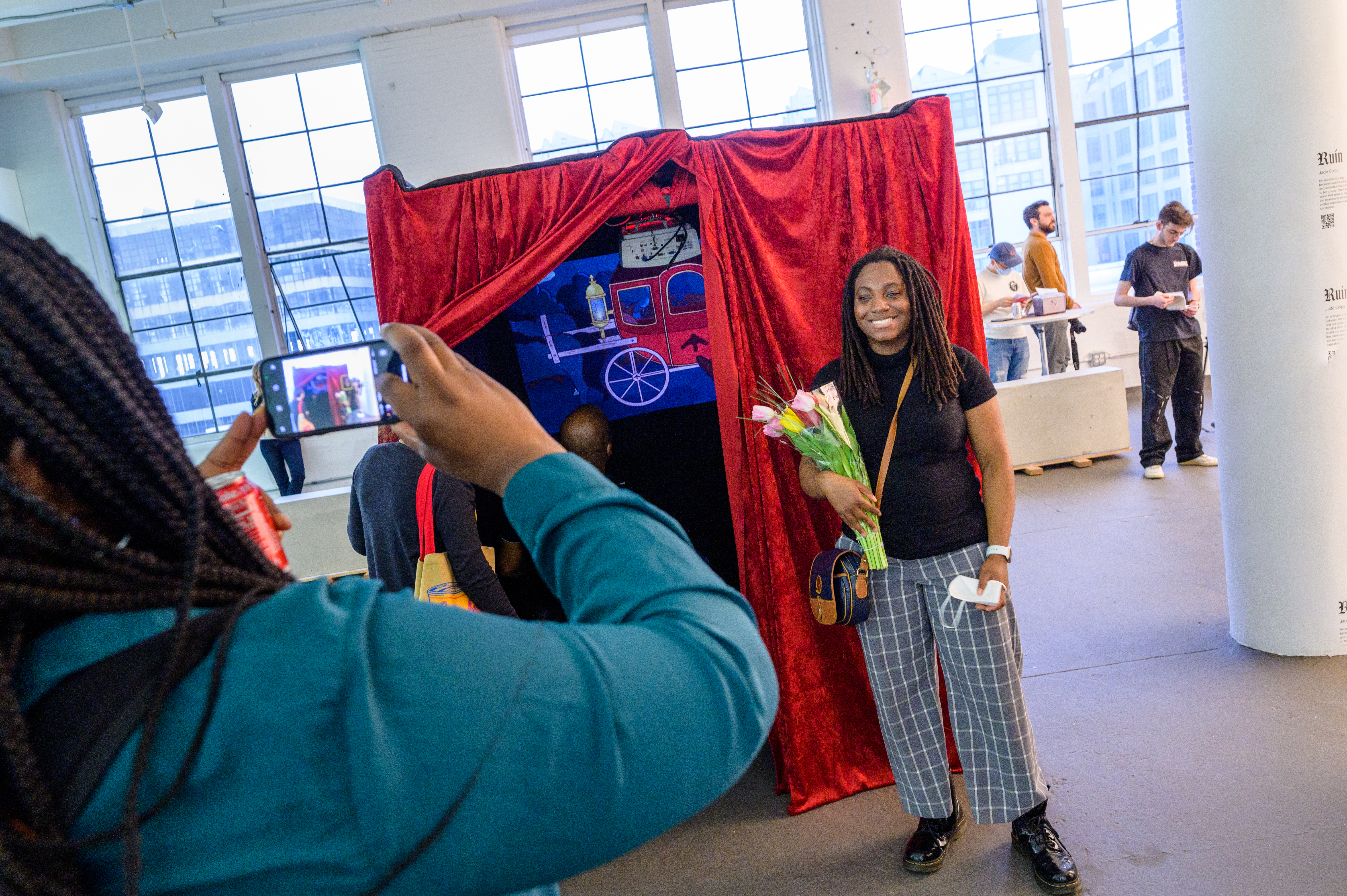 Student stands in front of her animation project at the visual arts and technology capstone exhibition.