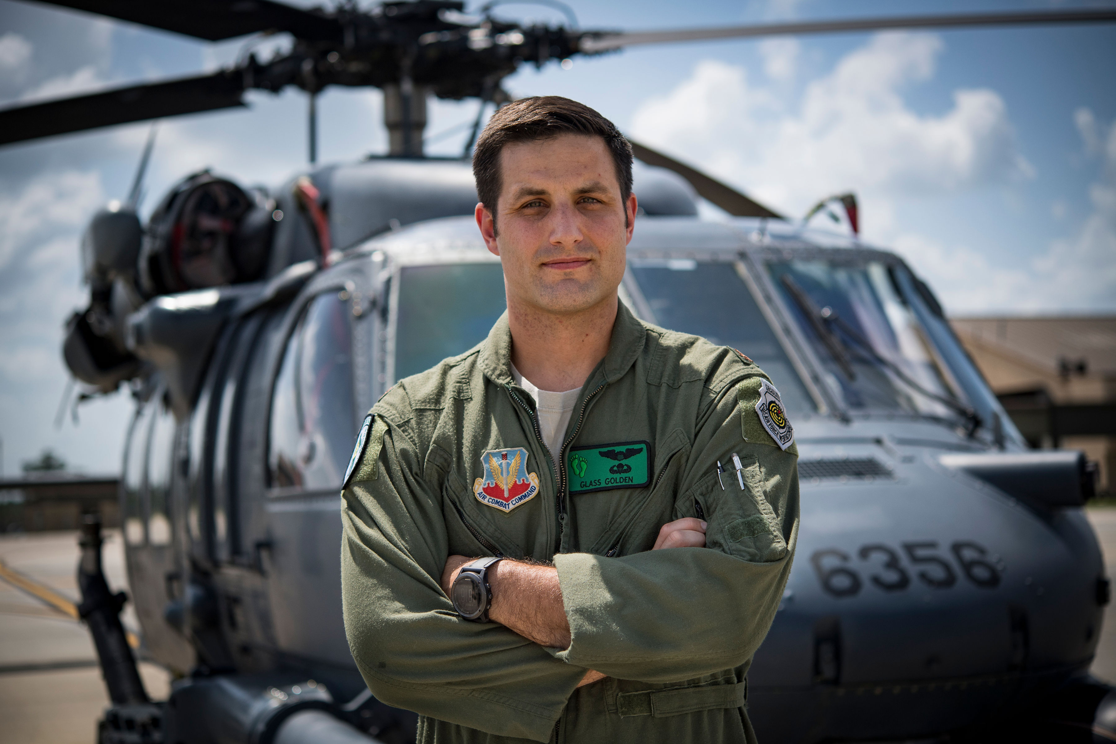 Pilot John Golden faces camera with helicopter behind him.