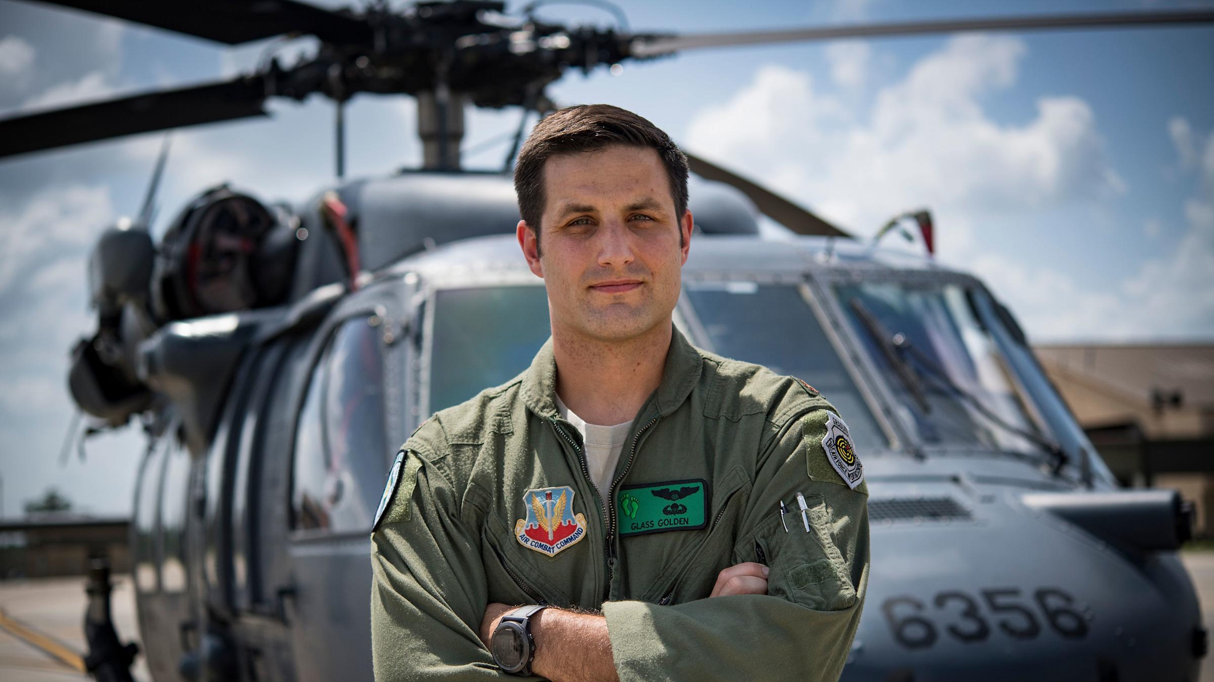 Pilot John Golden faces camera with helicopter behind him.