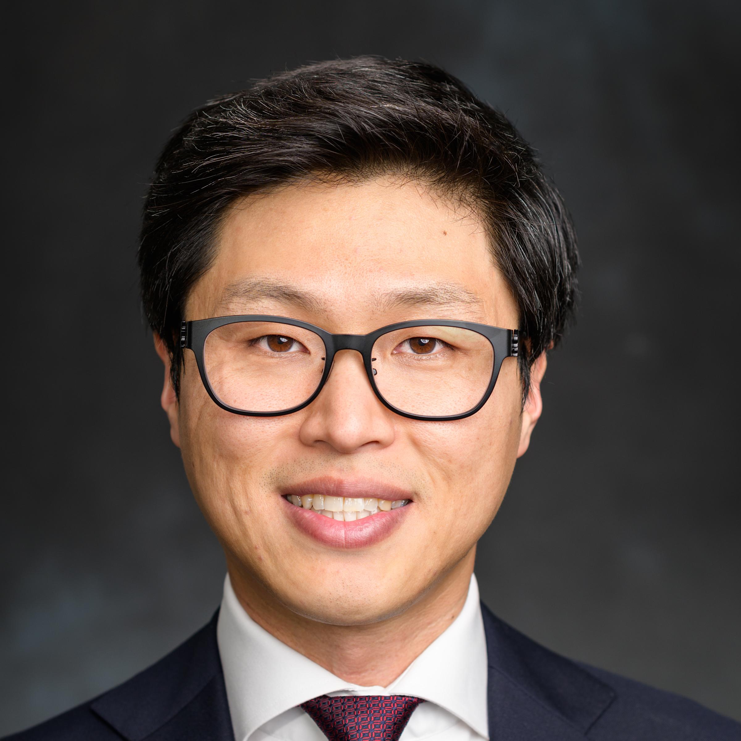 A professional headshot of Kwahun Lee. He is wearing glasses and a suit and tie.