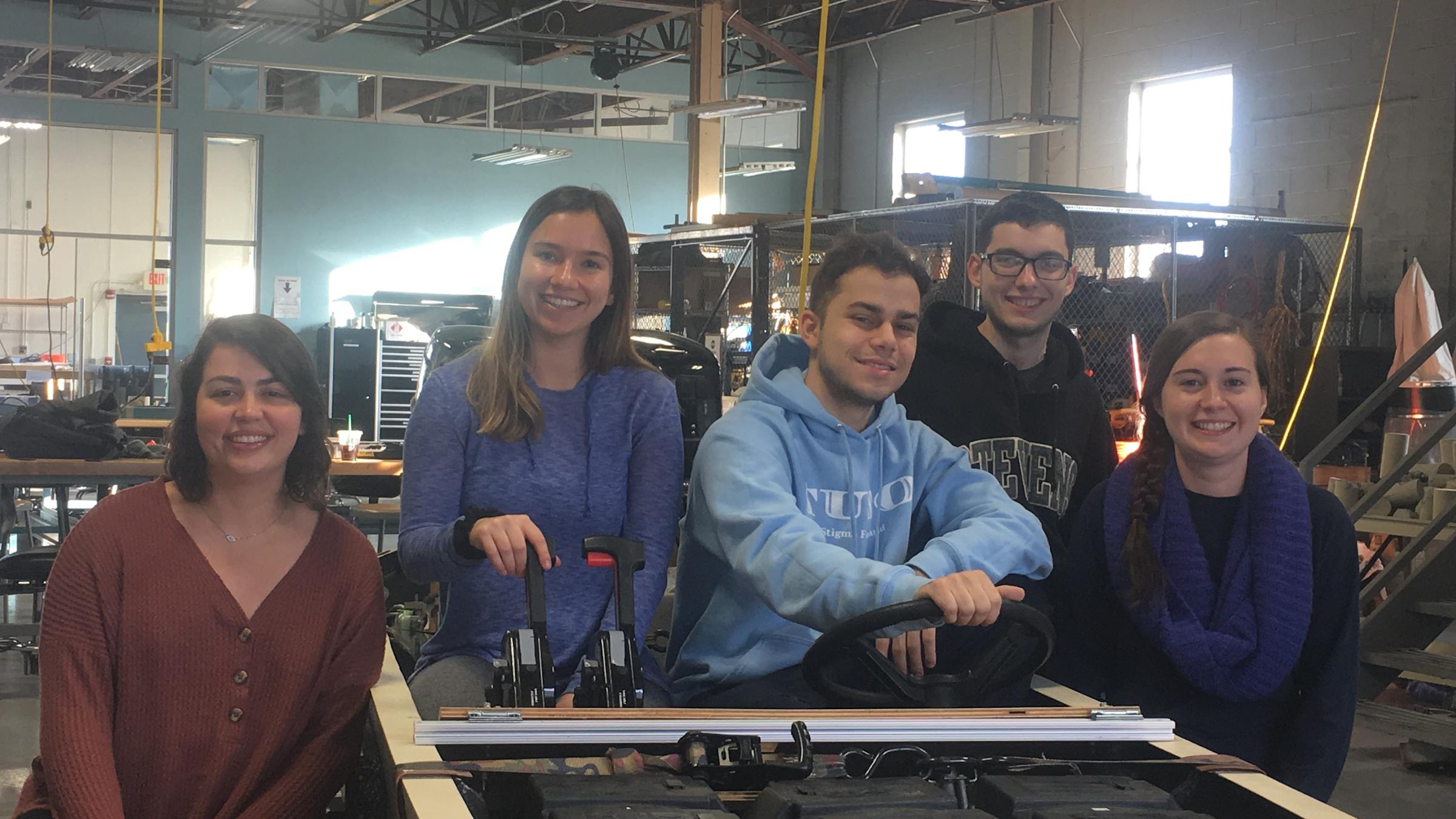 From left to right: Stevens' Solar Splash team members Victoria Davis ‘19, Melanie Valentin ‘19, Matthew Colacino ‘19, Justin Sitler ‘19 and Meghan Hand ‘19 pose around the competition boat inside the Griffith Building near Stevens campus