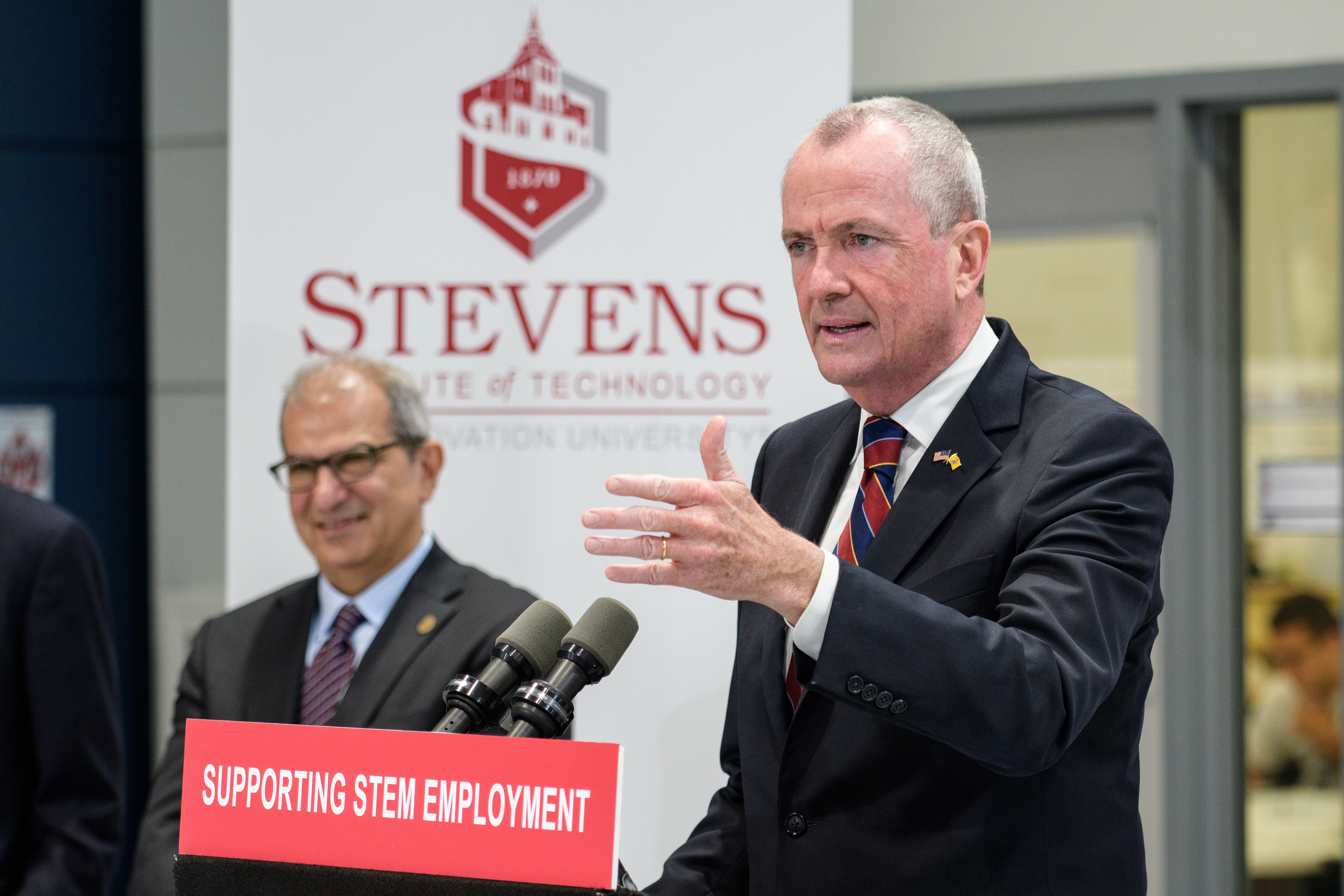 Gov. Phil Murphy speaking at the podium in the ABS  Engineering Center at Stevens Institute of Technology as President Nariman Farvardin looks on