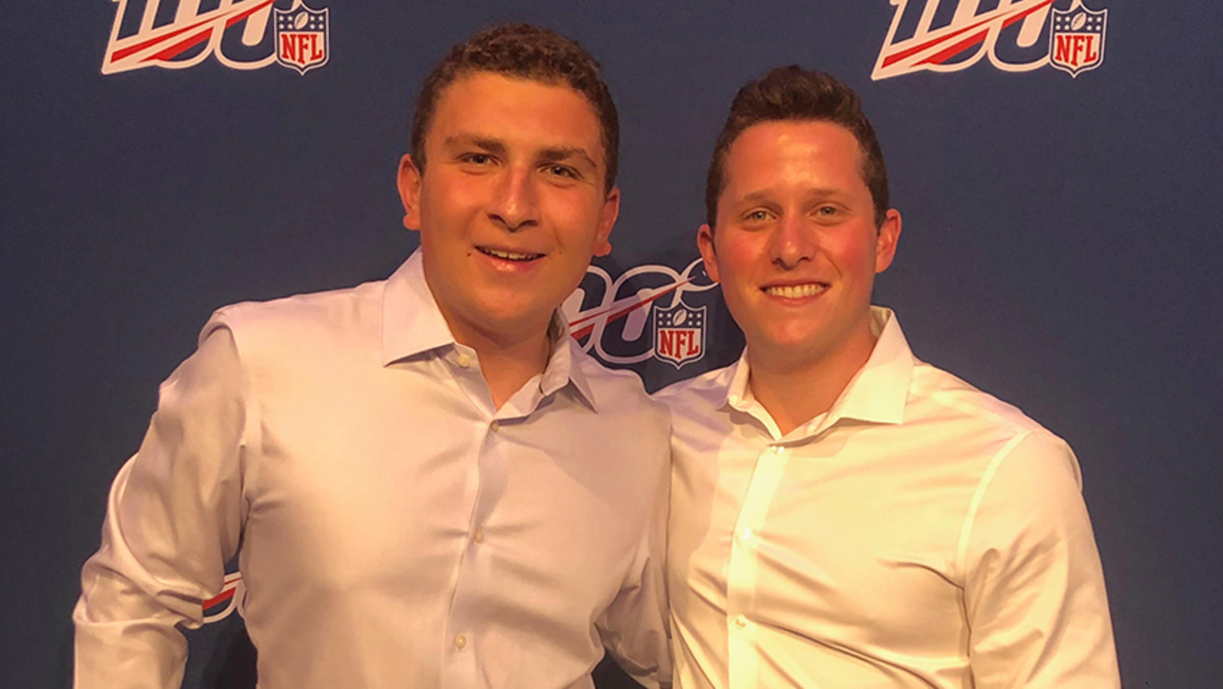 Two young men in front of a blue NFL step-and-repeat.