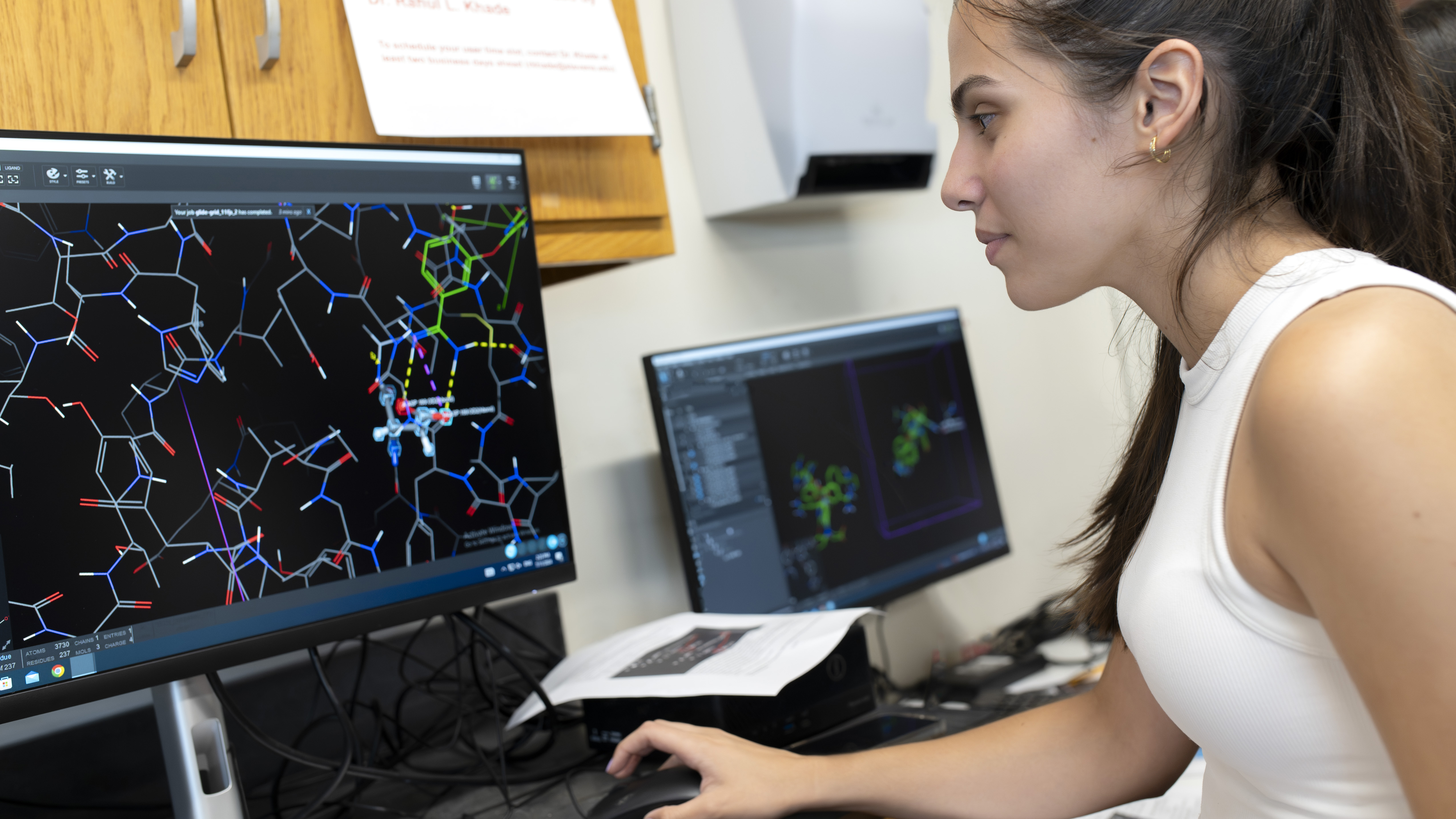A student in a computer lab working on a program showing atomic structures.