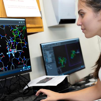 A student in a computer lab working on a program showing atomic structures.