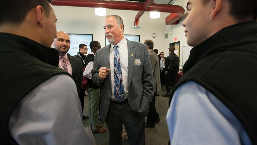 Dr. Don Lombardi surrounded by a group of students at the Stevens campus.