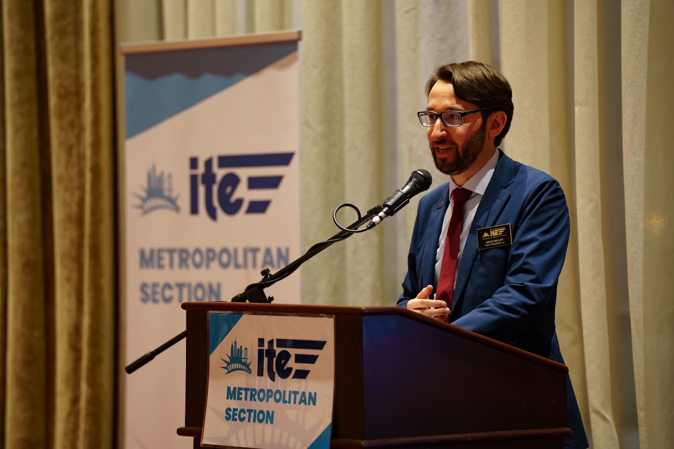 Brad Miller ’06 M.Eng. ’08 presents on stage behind a podium for the event ITE - Metropolitan Section