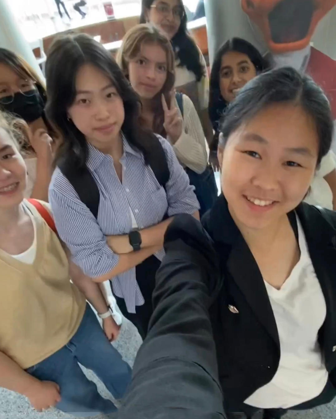 Students take a selfie in front of the windows at the Babbio Center.