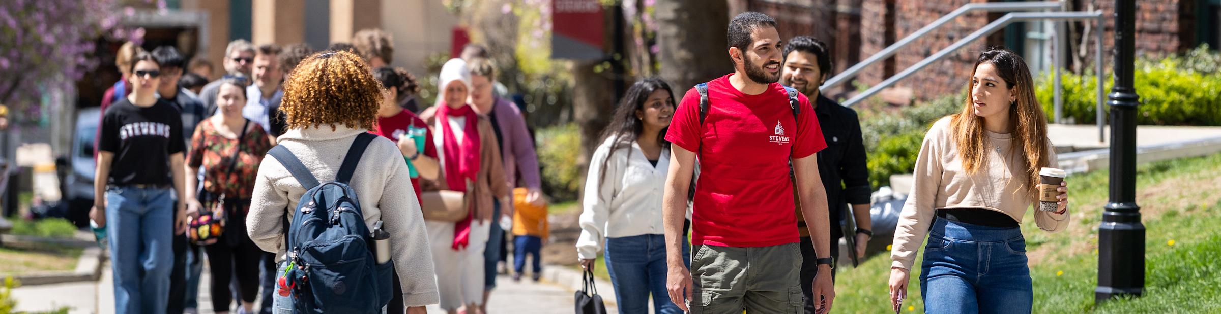 Male and female students walk on campus on a sunny day