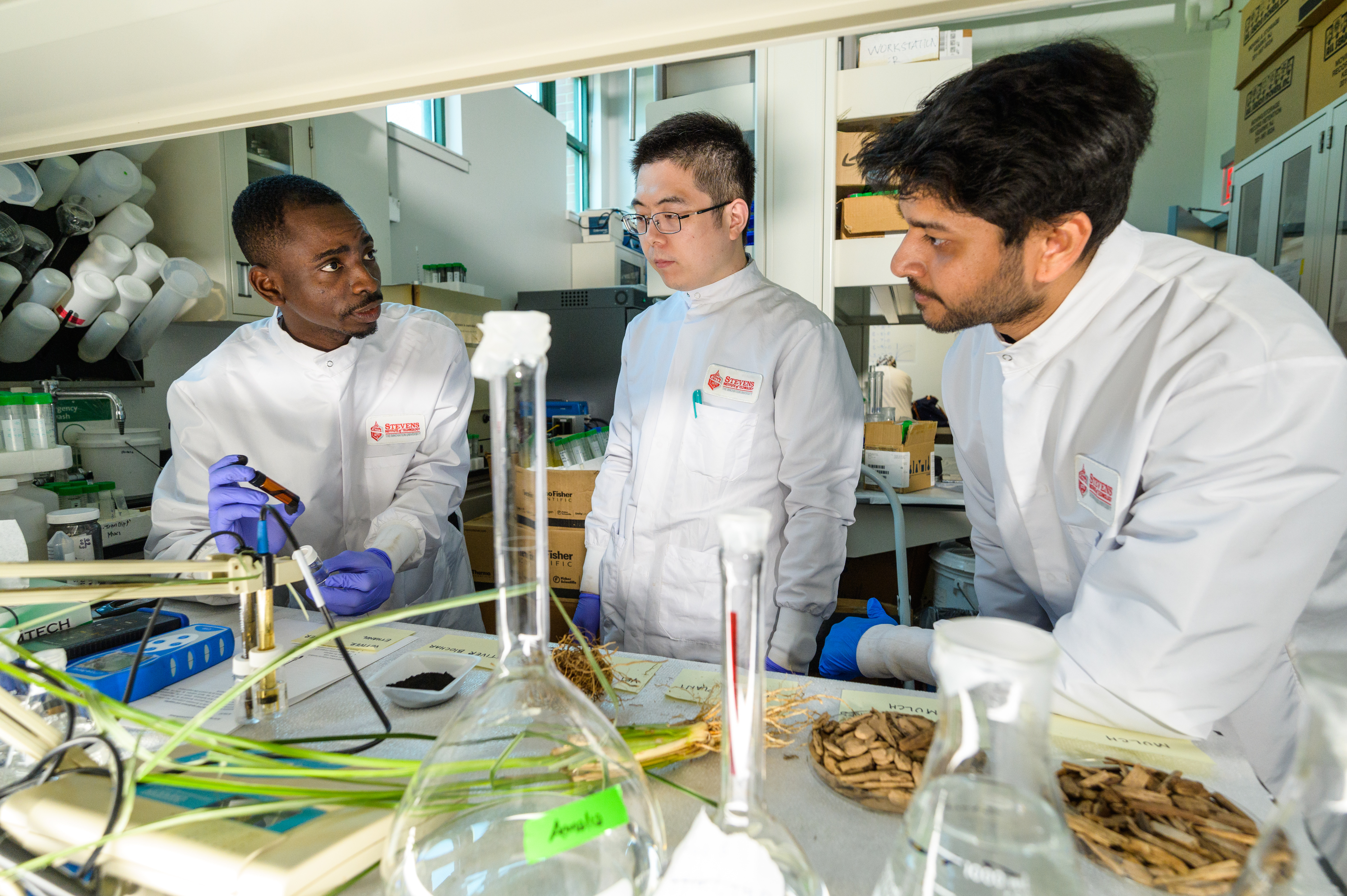 three graduate students testing materials in lab