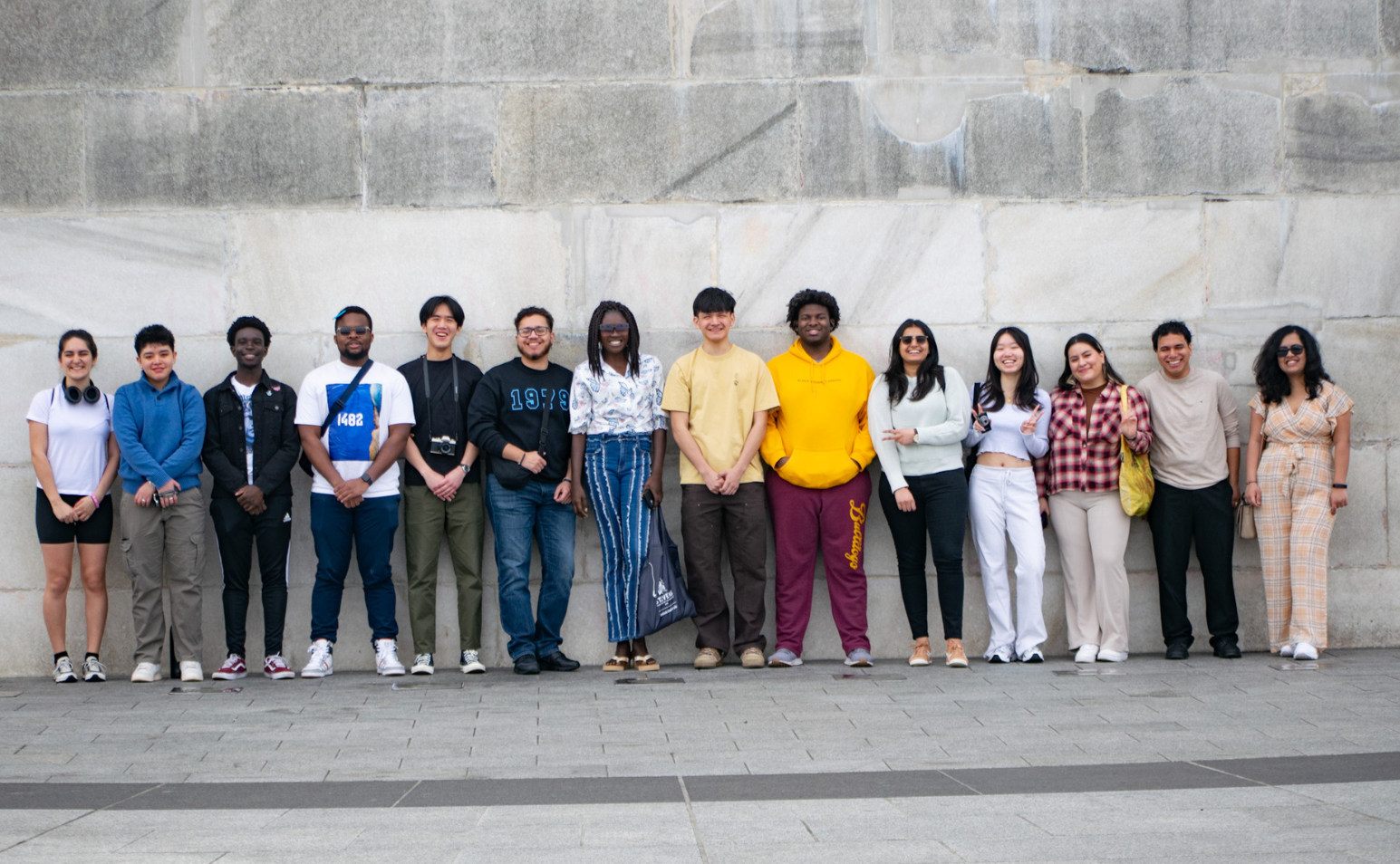 a group of students standing by a stone wall