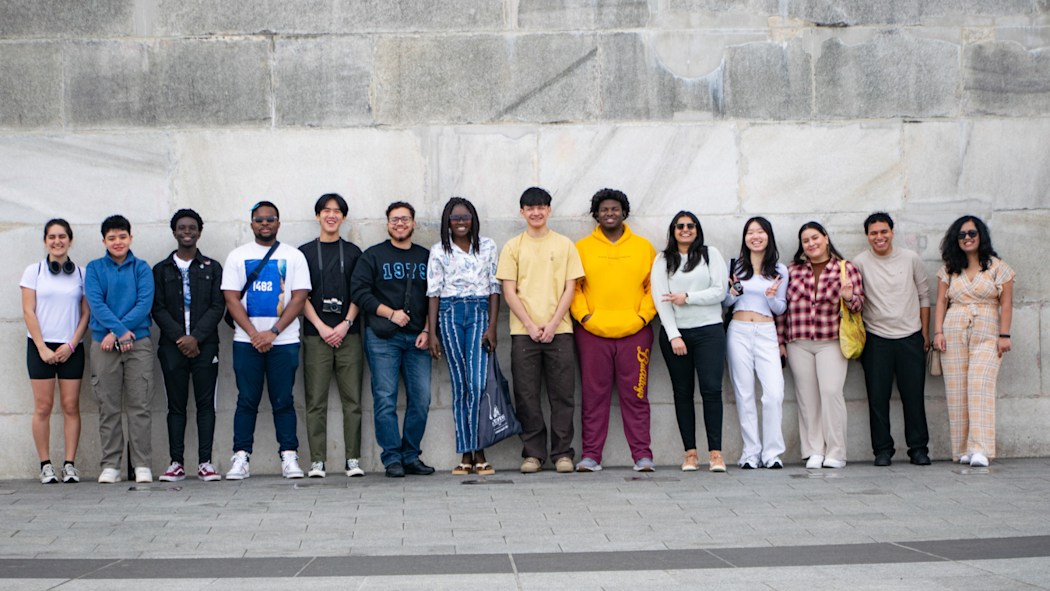 a group of students standing by a stone wall