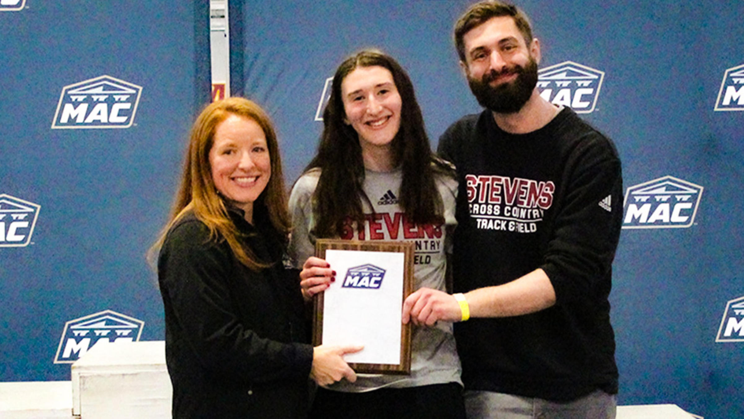 Laura Mathews receives a MAC track and field award with her coaches.
