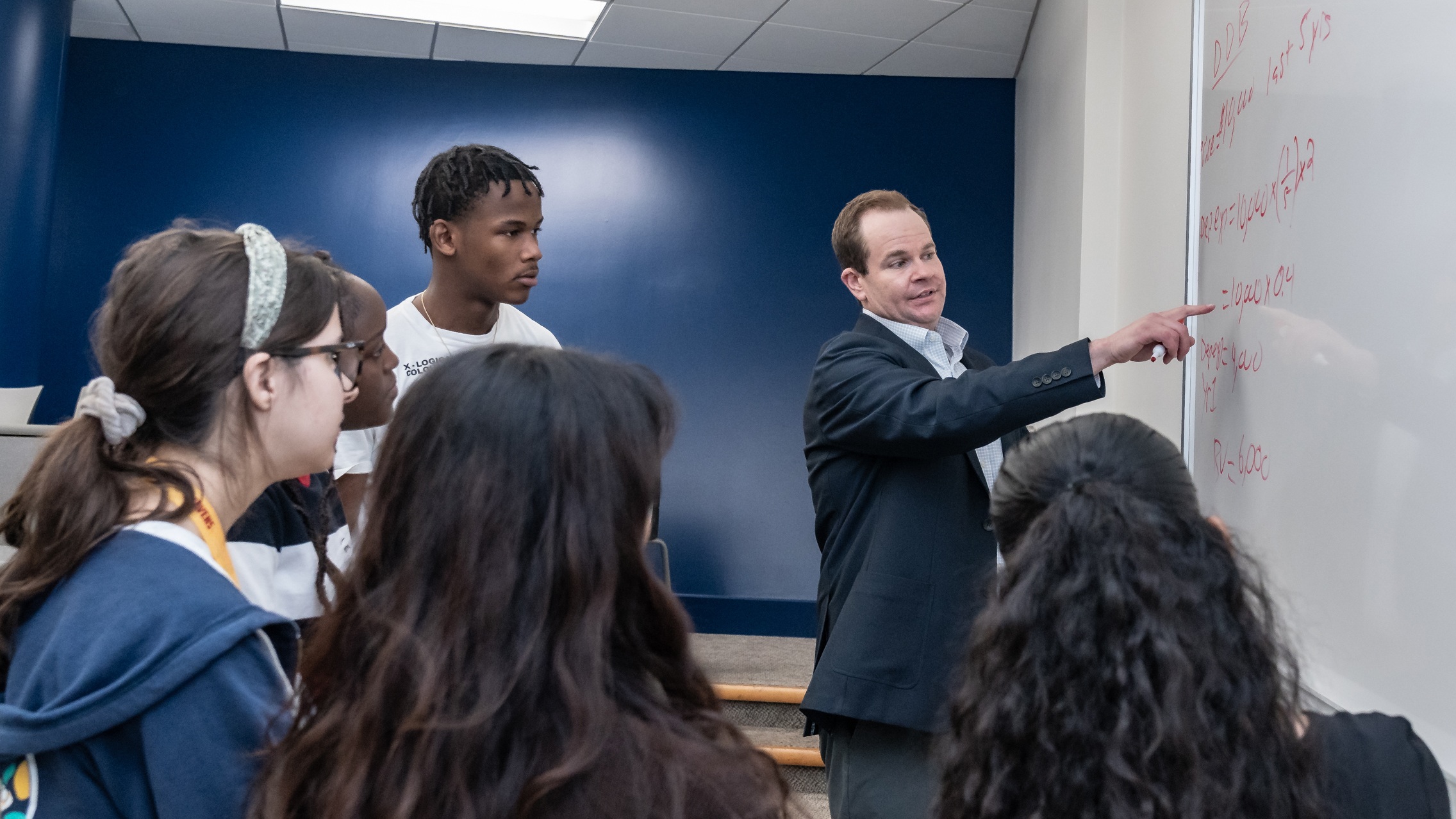 Professor at white board teaching with students
