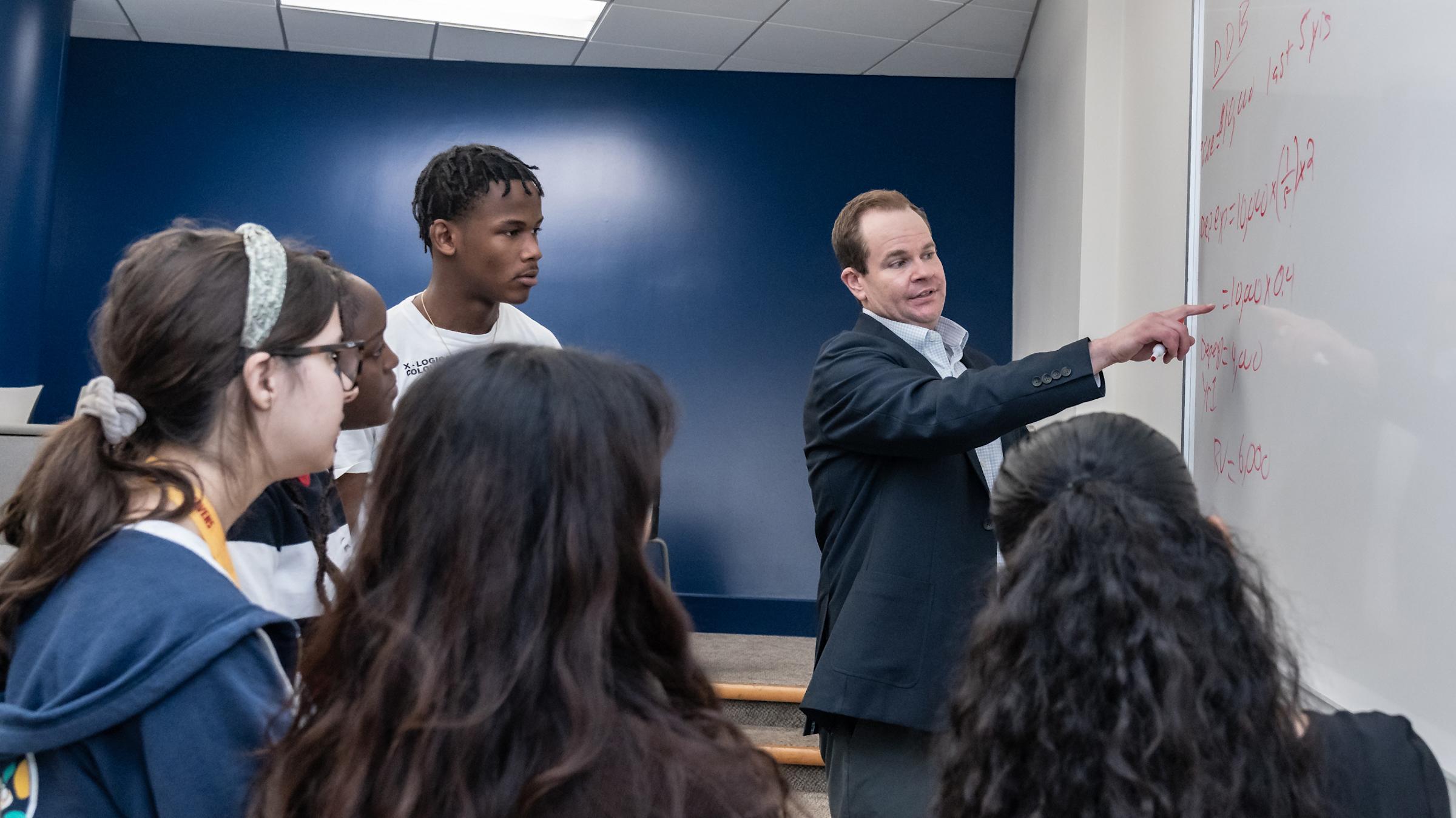 Professor at white board teaching with students