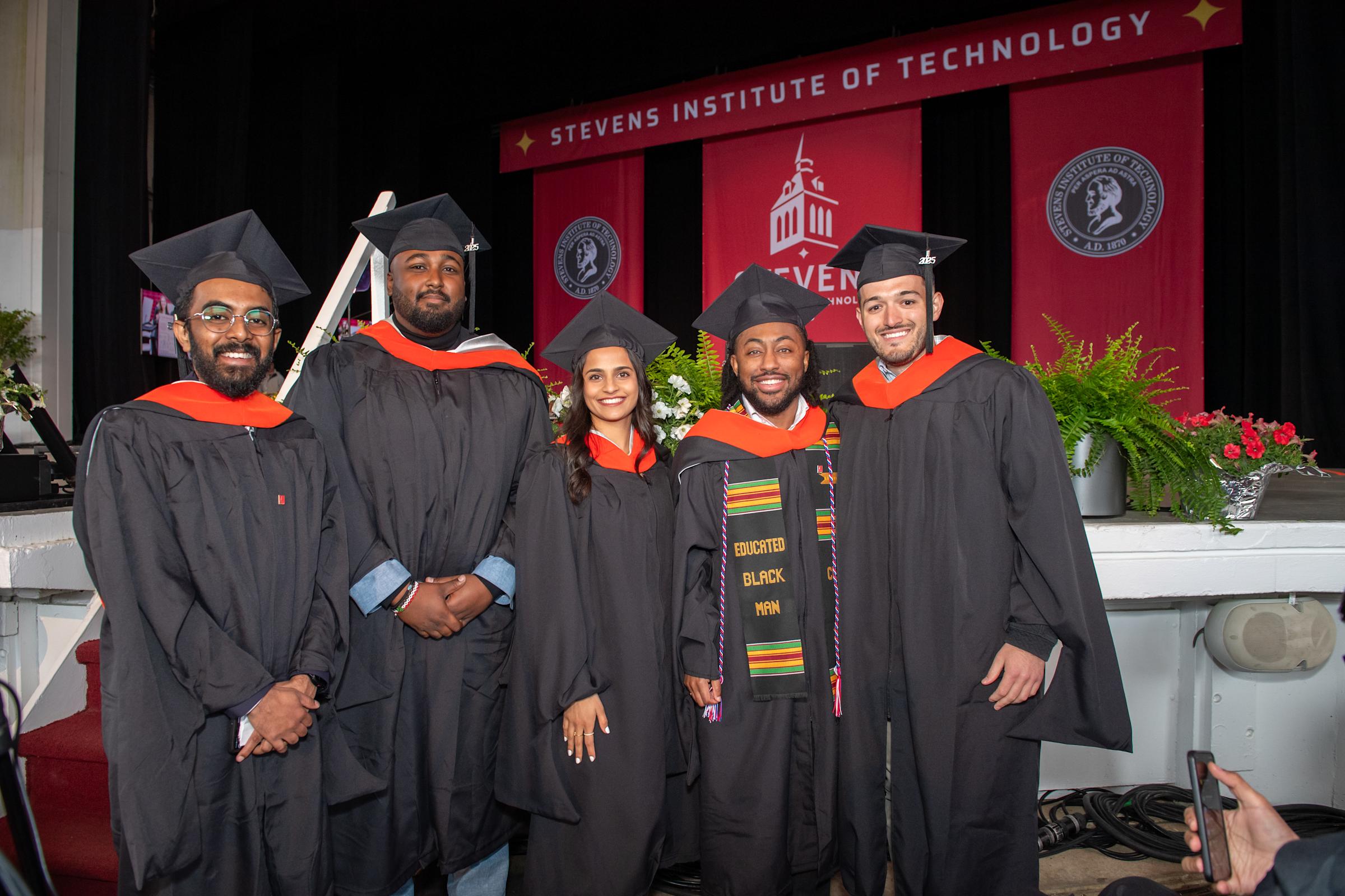 Five graduate students pose at Commencement.