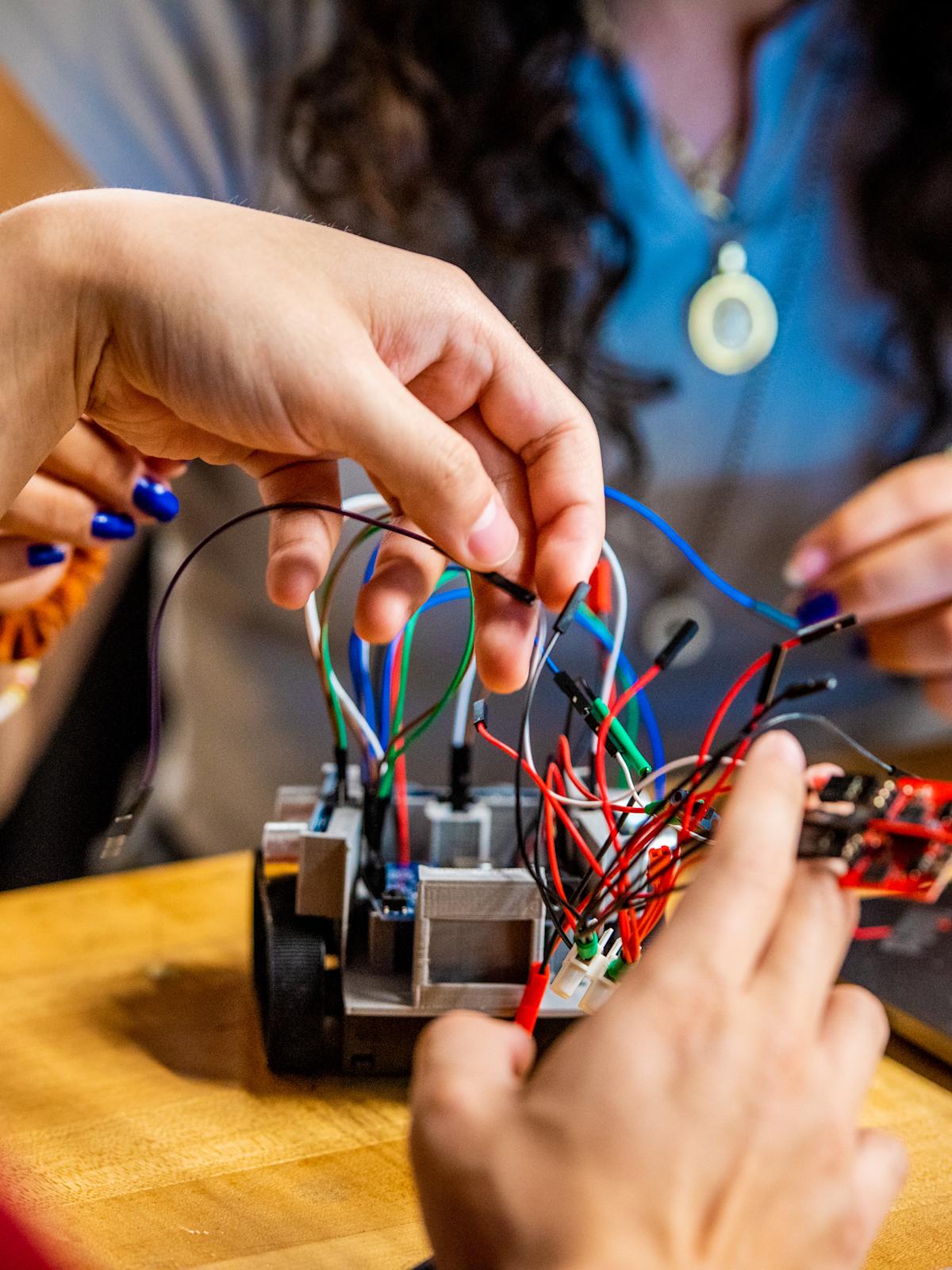 Student twisting wires on small robot