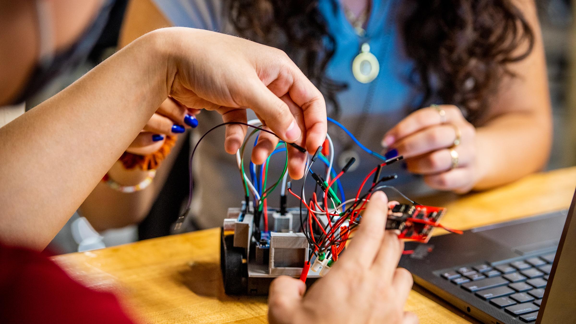 Student twisting wires on small robot