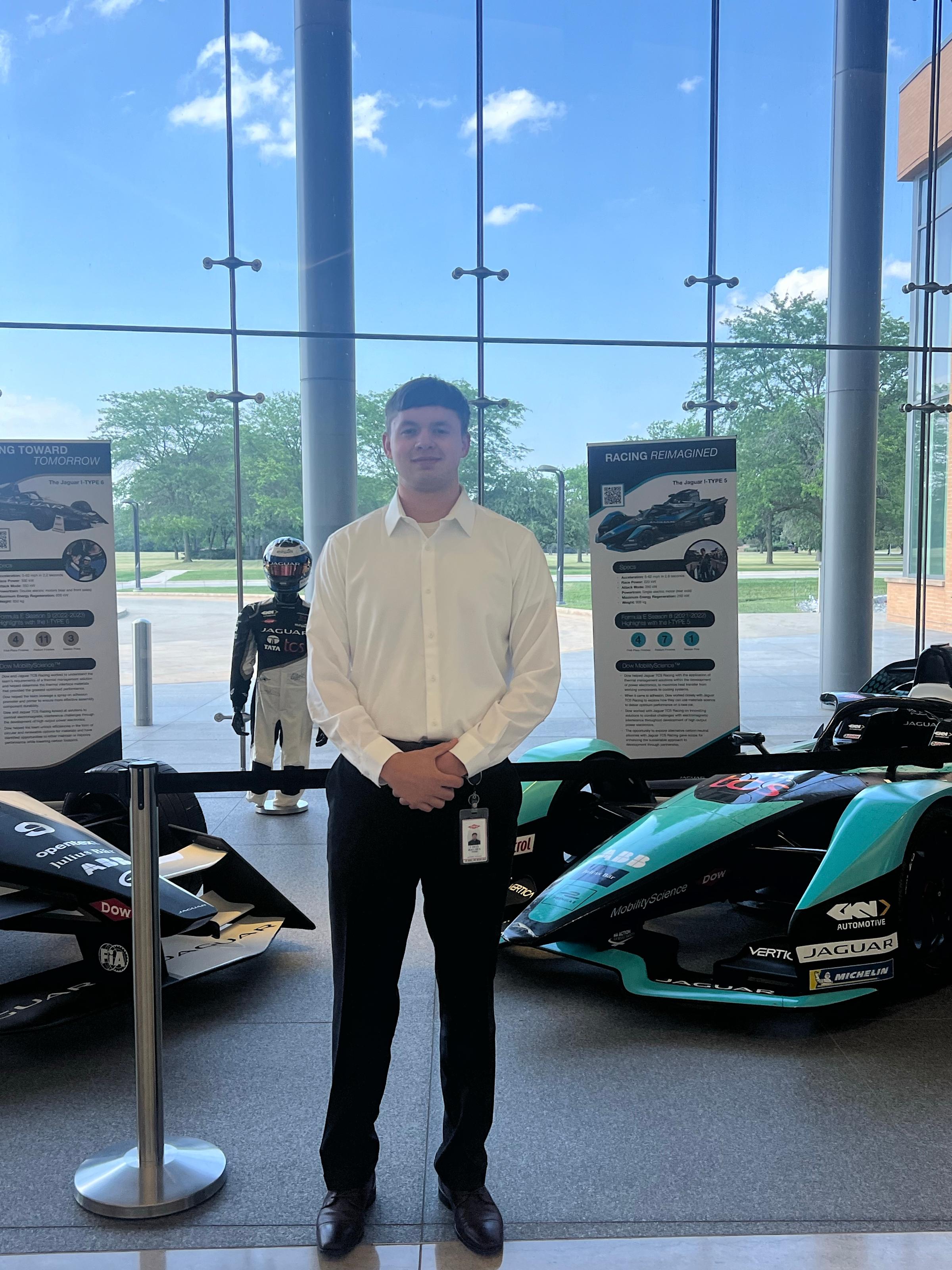 Ethan Boucher stands in front of a Formula E race car.