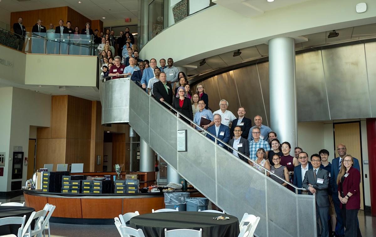 Attendees of the AiBC Community inaugural session pose on a spiral staircase at Babbio Center.