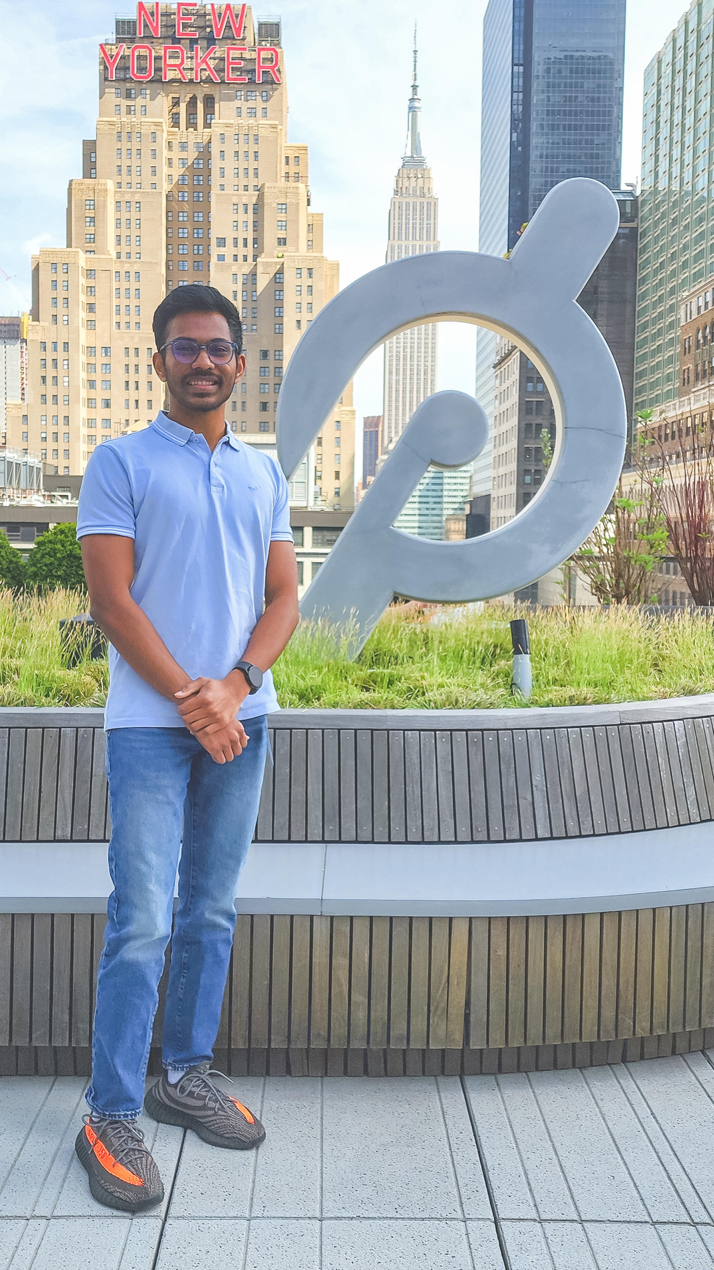 Aaryan Yekkisetty poses with a metal plaque representing the Peloton logo outside Peloton's New York City office.