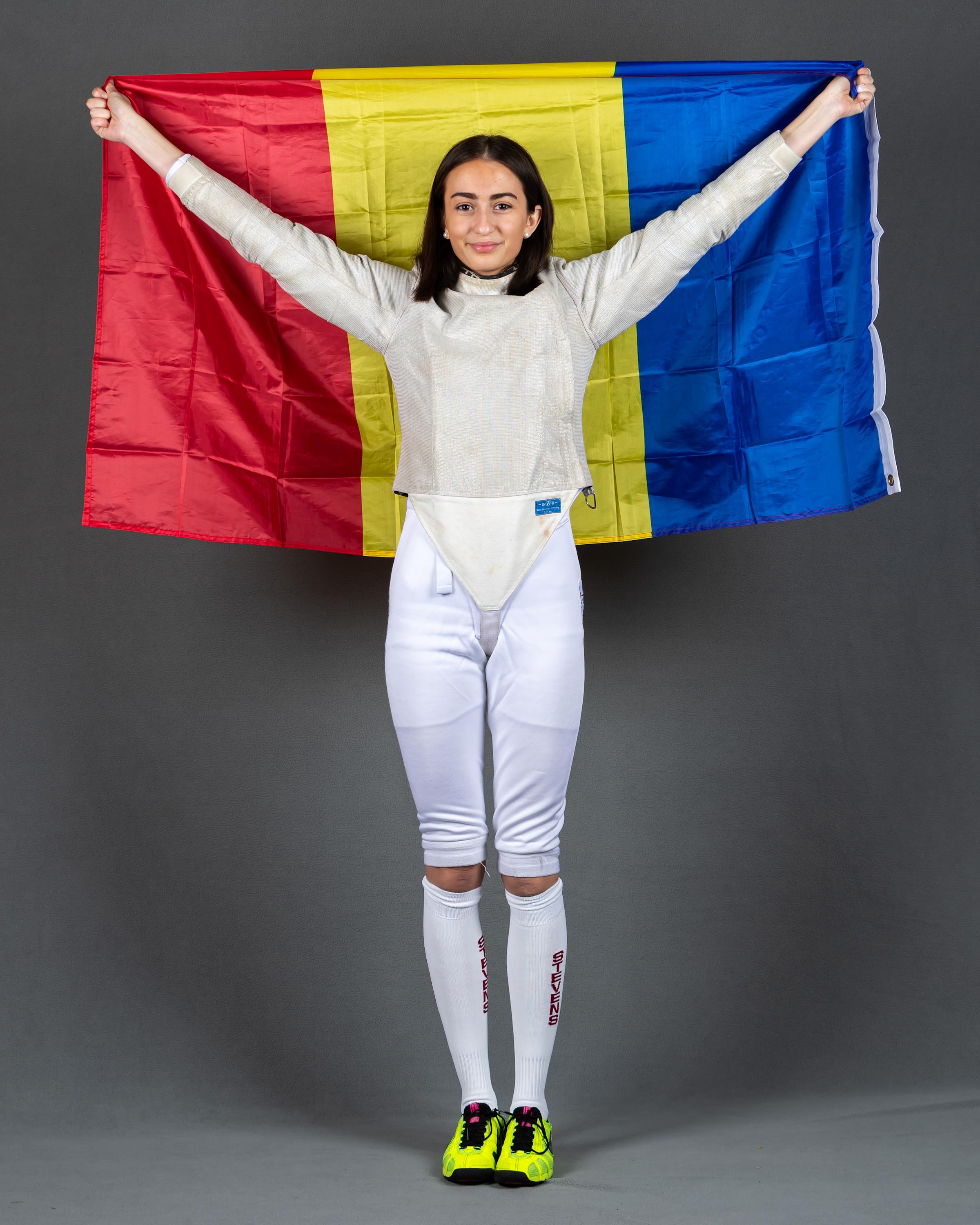 Arianna Daringa in her fencing uniform holding the Romanian over her head. 