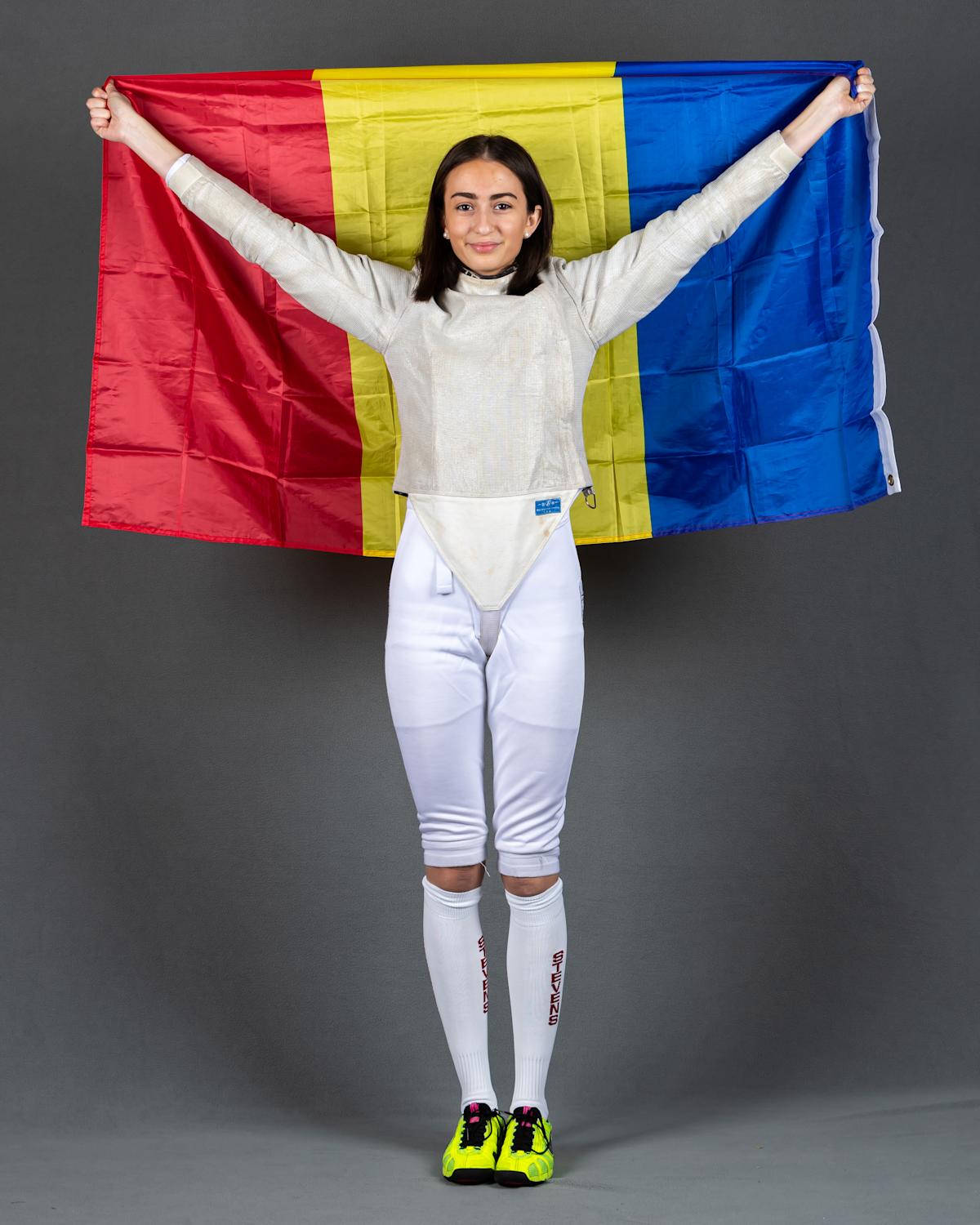 Arianna Daringa in her fencing uniform holding the Romanian over her head. 