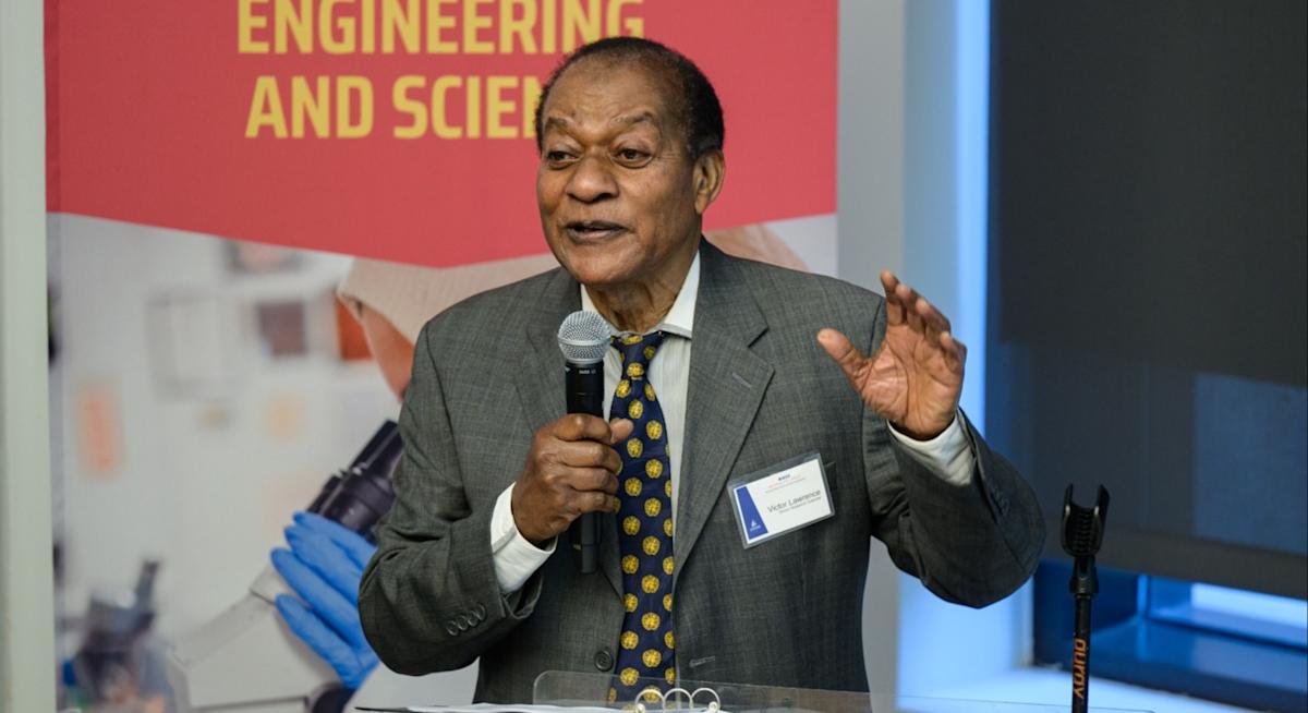 Victor Lawrence speaking at a podium with a banner on the left that reads "Schaefer, Jr. School of Engineering and Science".