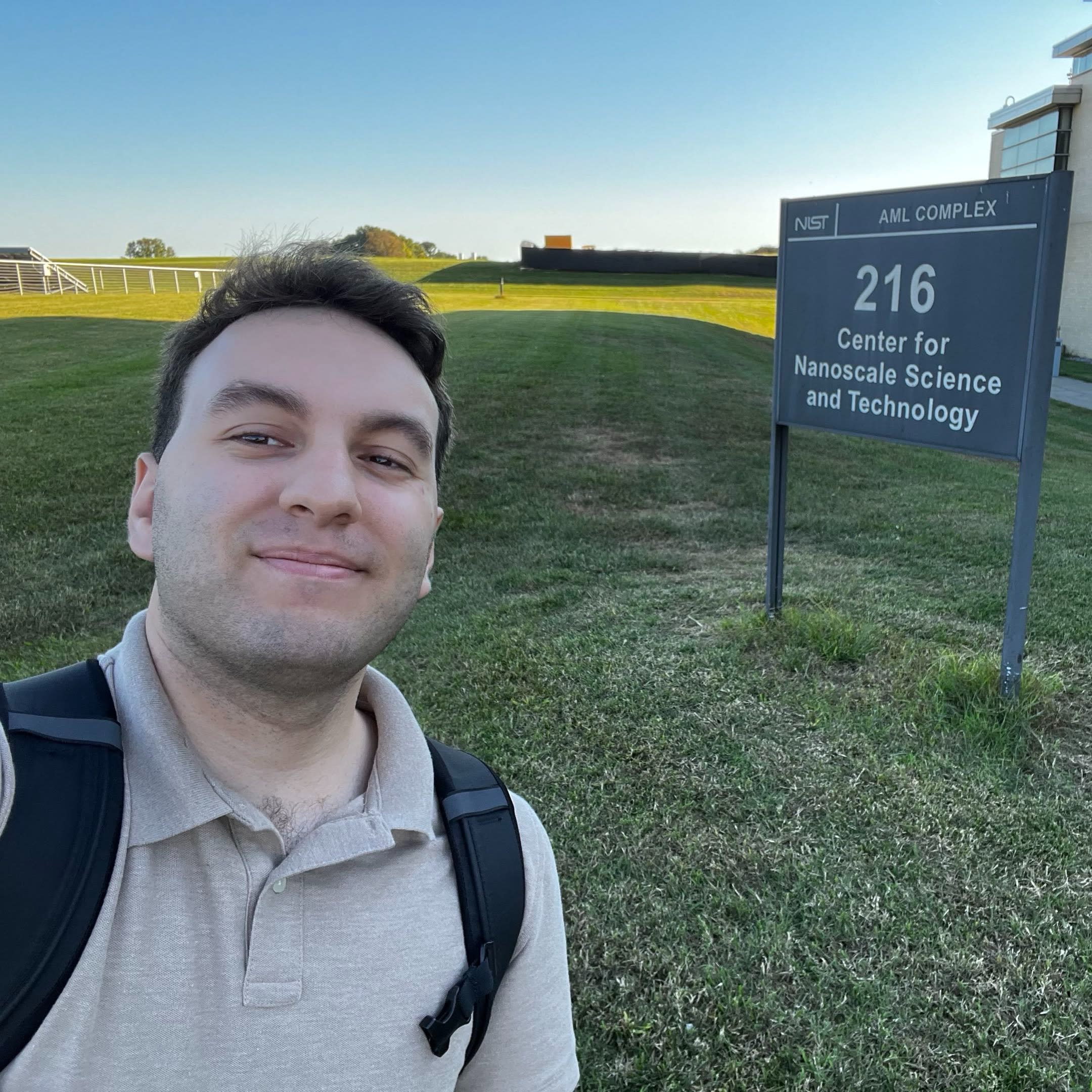 Christopher Kniss taking a selfie outside in front of a sign that reads 216 Center for Nanoscale Science and Technology