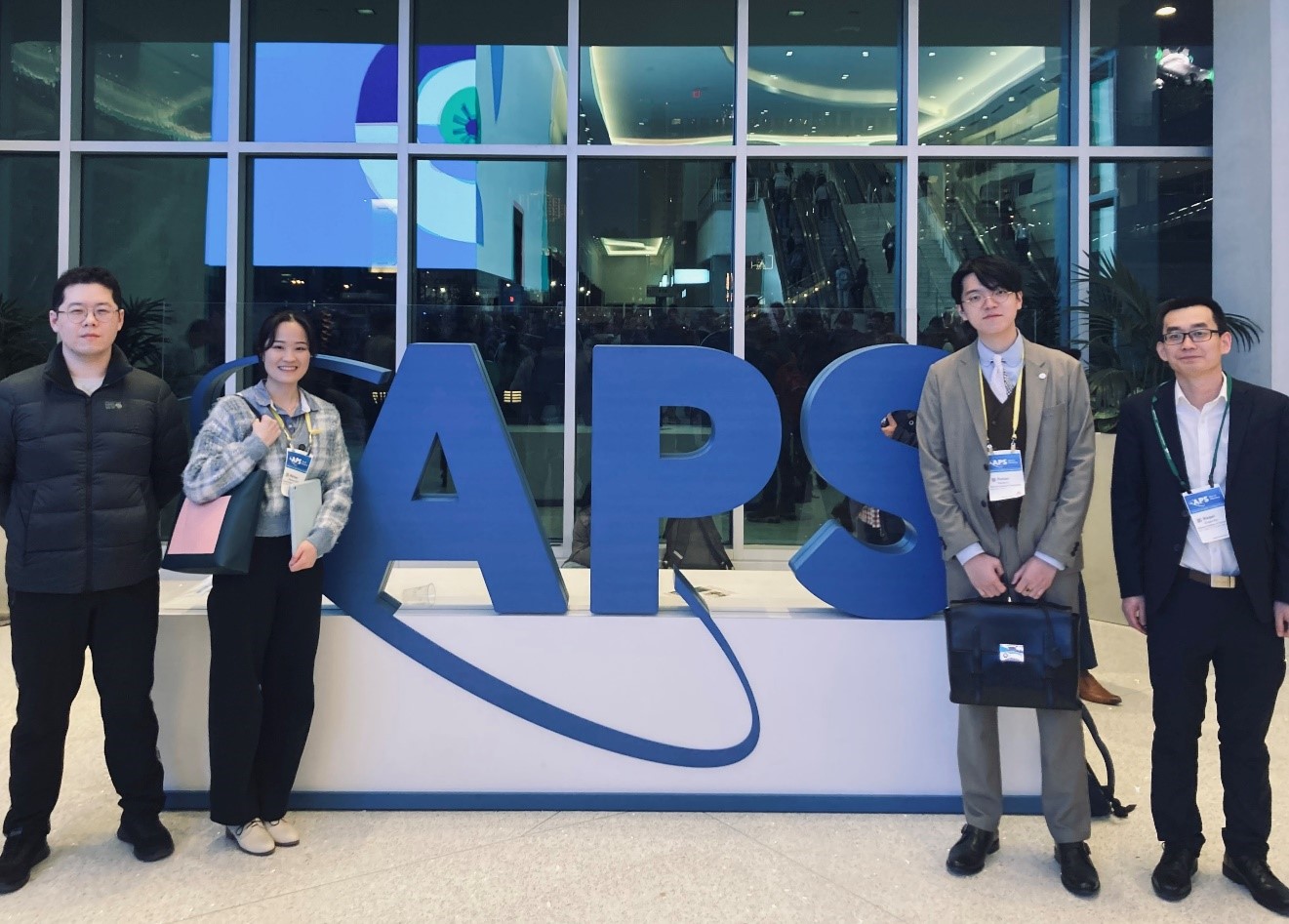 Several Stevens students stand in front of a big APS sign.