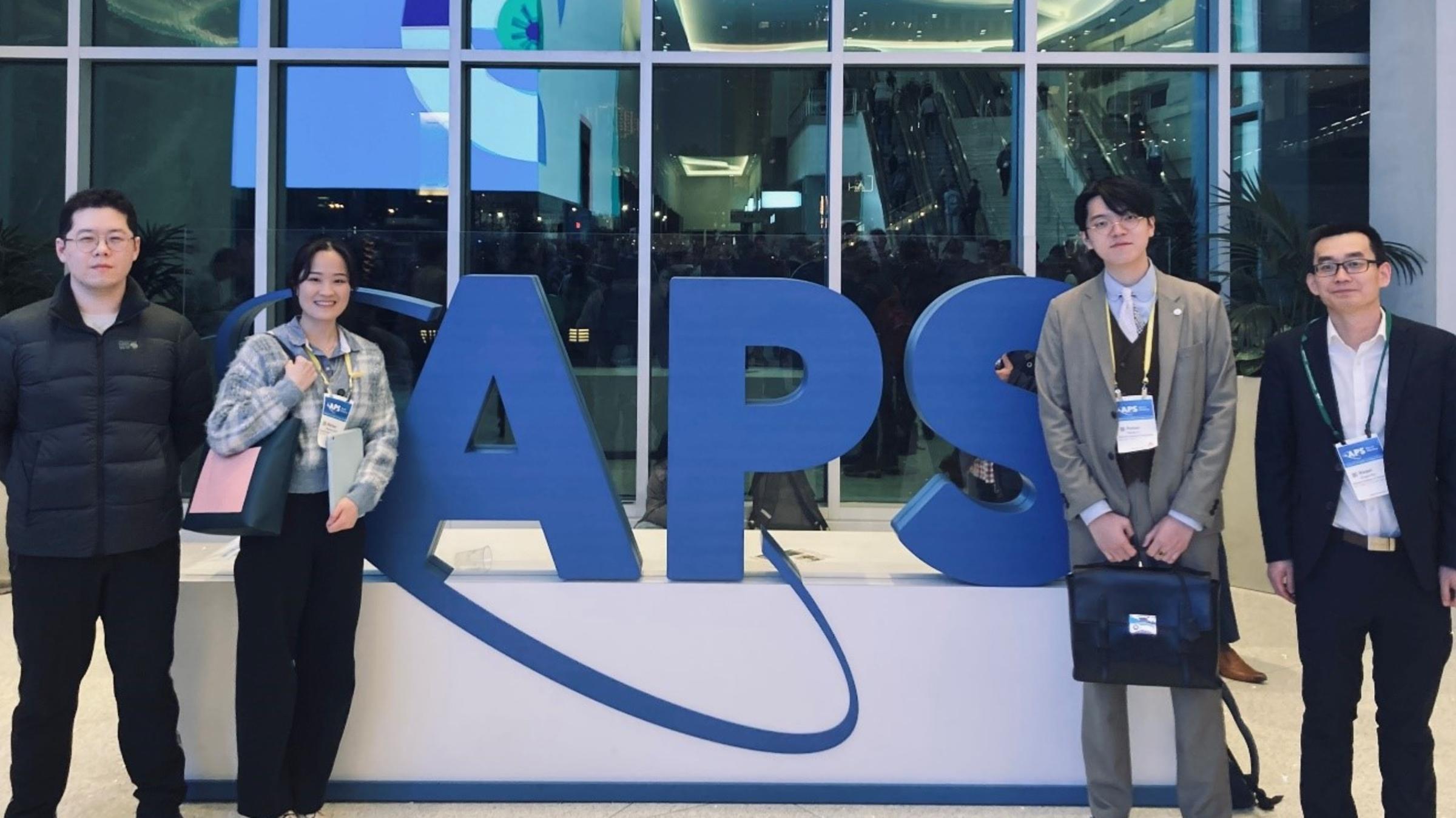 Several Stevens students stand in front of a big APS sign.