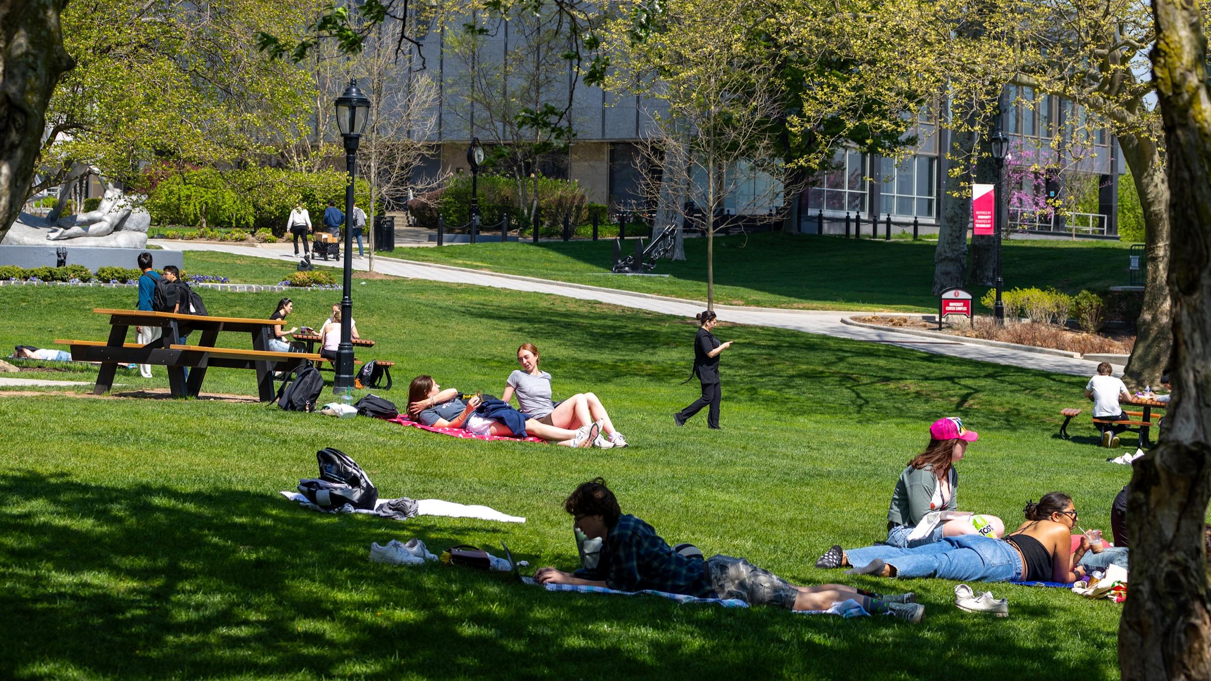 Students relaxing on campus lawn on a sunny spring day.