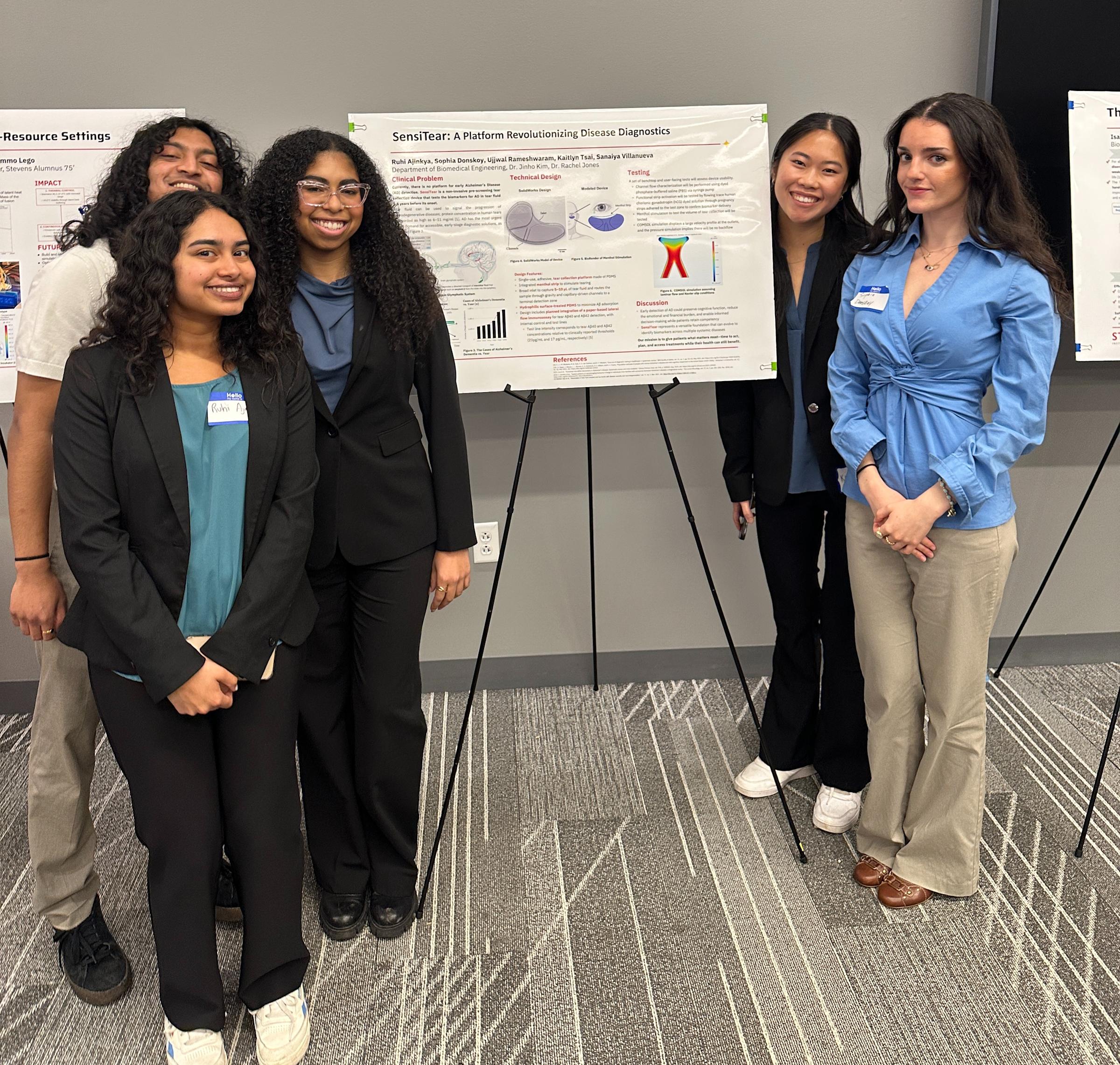 A group of five biomedical engineering students gather around their research poster for a photo.