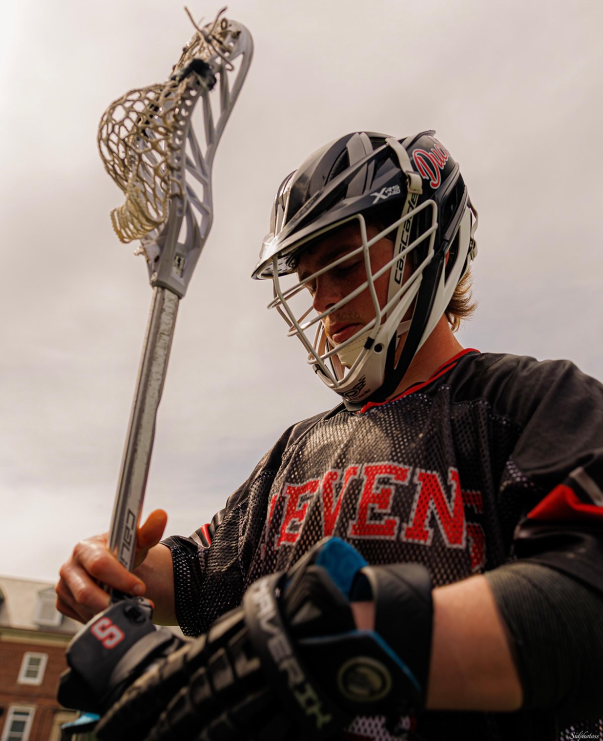 Luke Lesizza puts on his gloves for a lacrosse game
