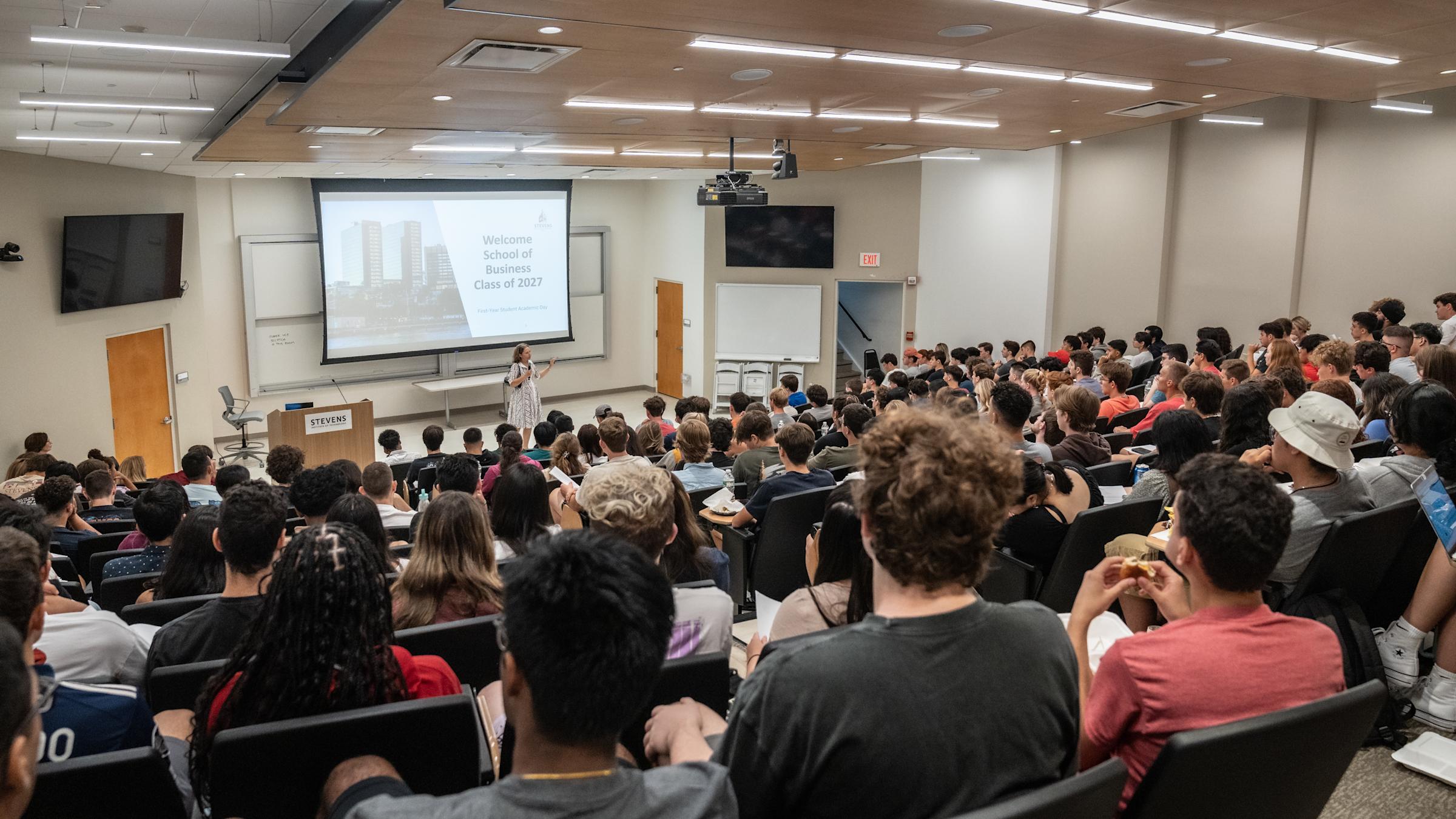Joelle Saad-Lessler speaks in front of group of first-year students in large auditorium
