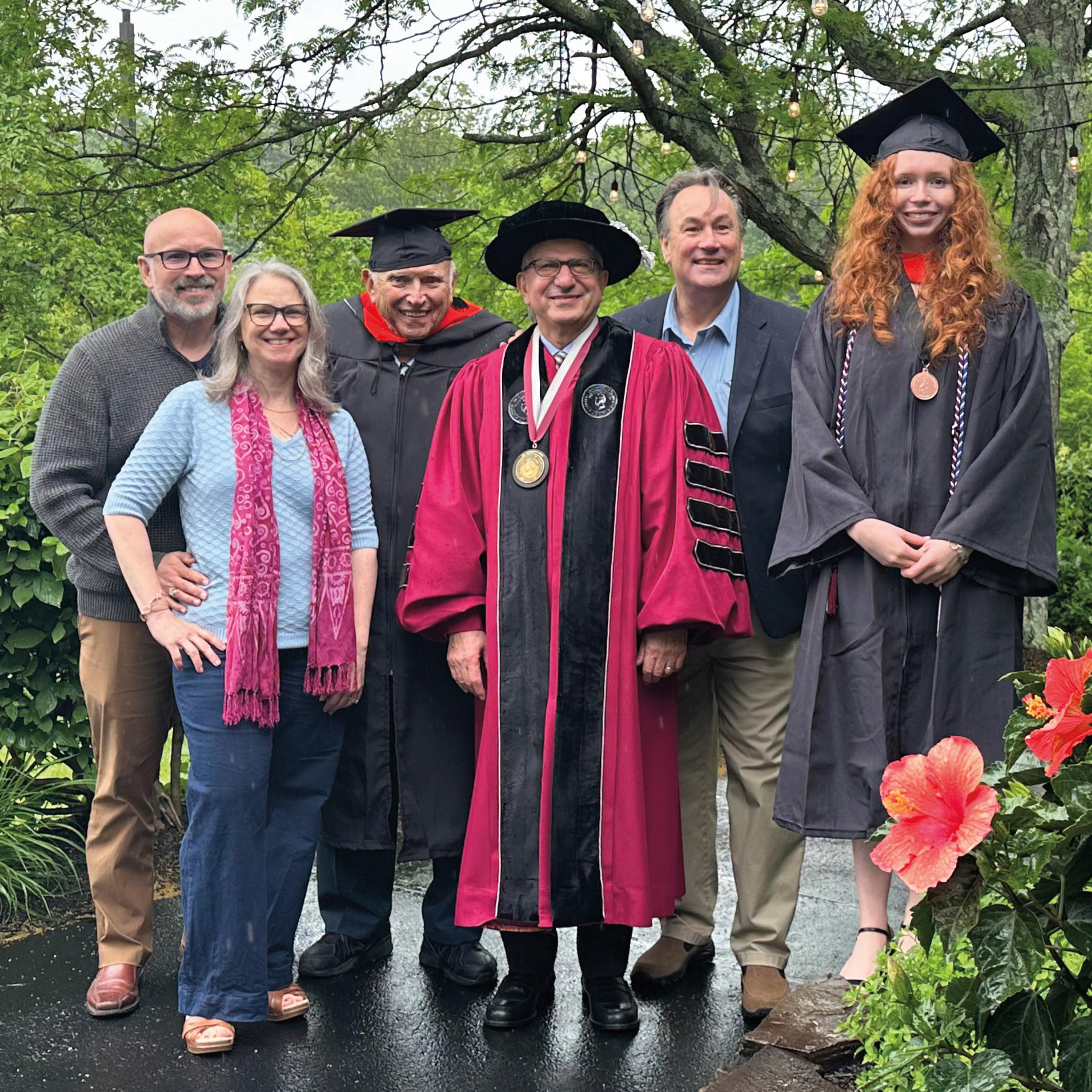 Photo of five members of the Stadelmann family and Stevens President Nariman Farvardin, surrounded by trees and flowers, at Commencement 2025.