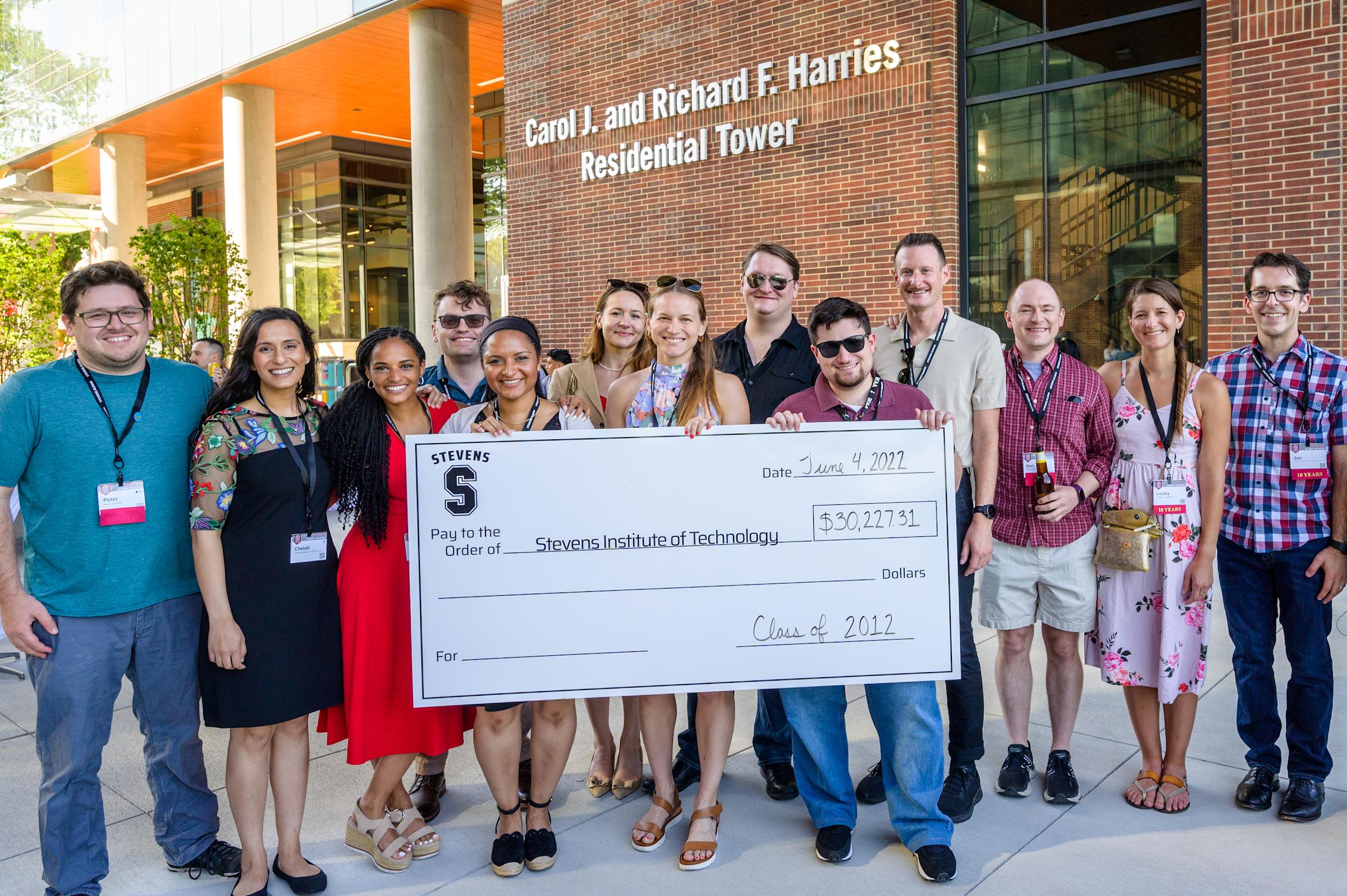 Members of the Class of 2012 pose outside the Harries Residential Tower with a large check at Alumni Weekend