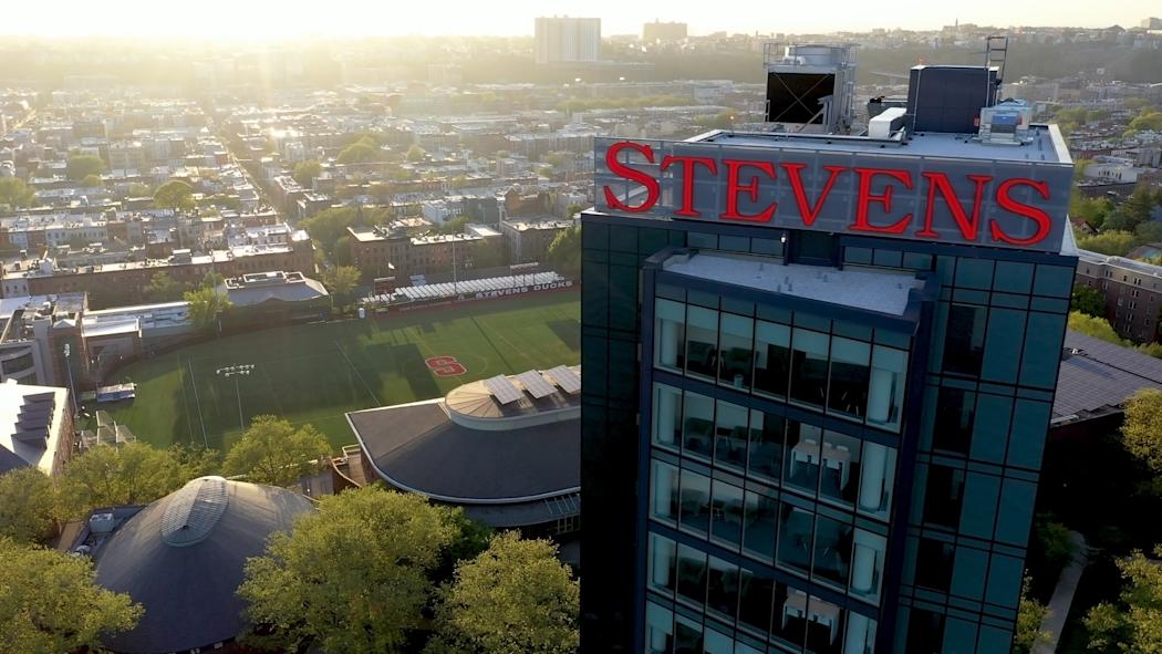 Aerial view of sign on top of the UCC with campus and Hoboken in background.