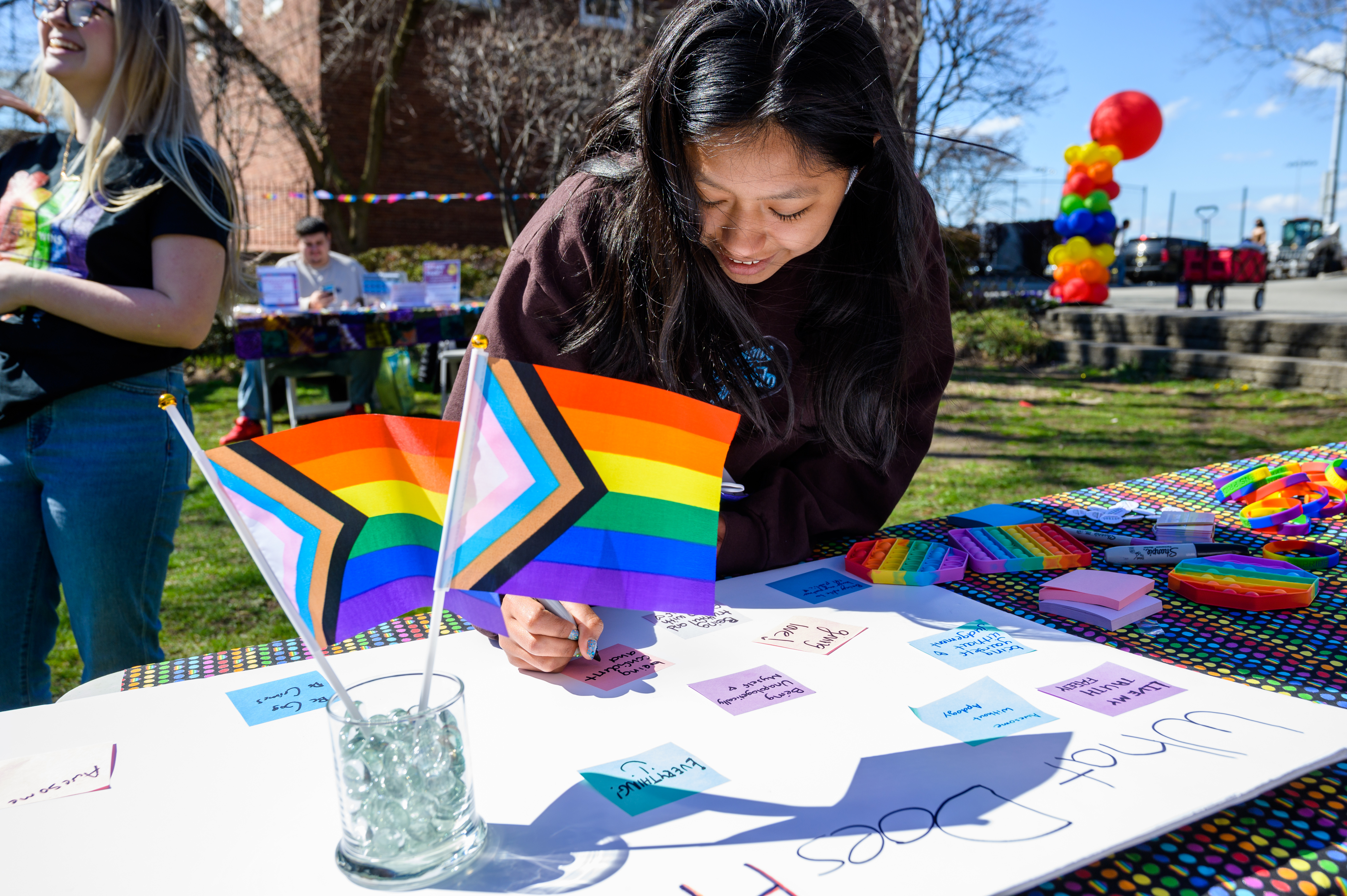 student signing a poster at the LGBTQ resource fair